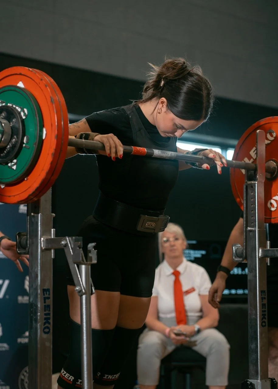 A woman preparing to squat at a powerlifting competition