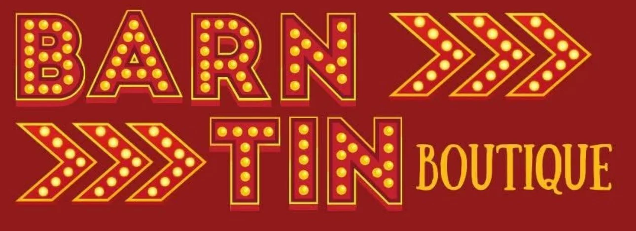Sign for 'Barn TIN Boutique' with bold, illuminated marquee-style letters and arrows on a red background.