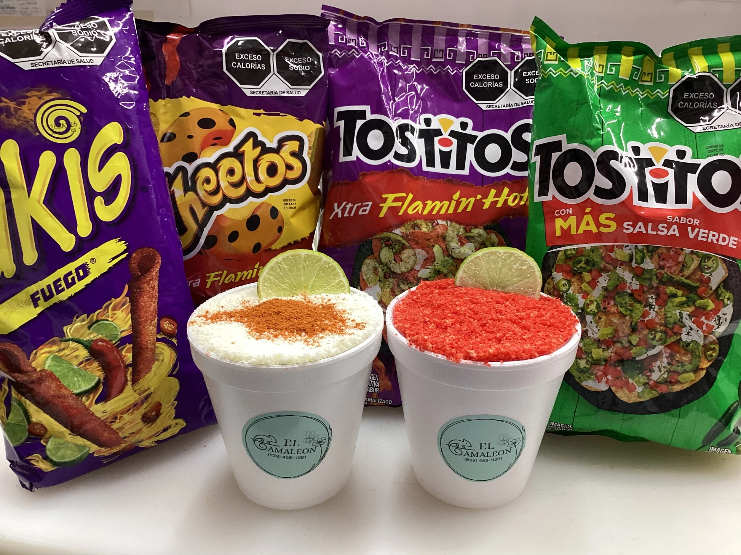 Two cups of Mexican-style crushed ice with lemon slices and chili powder, placed in front of three bags of flavored potato chips, including Fuego, Flamin' Hot, and Salsa Verde.