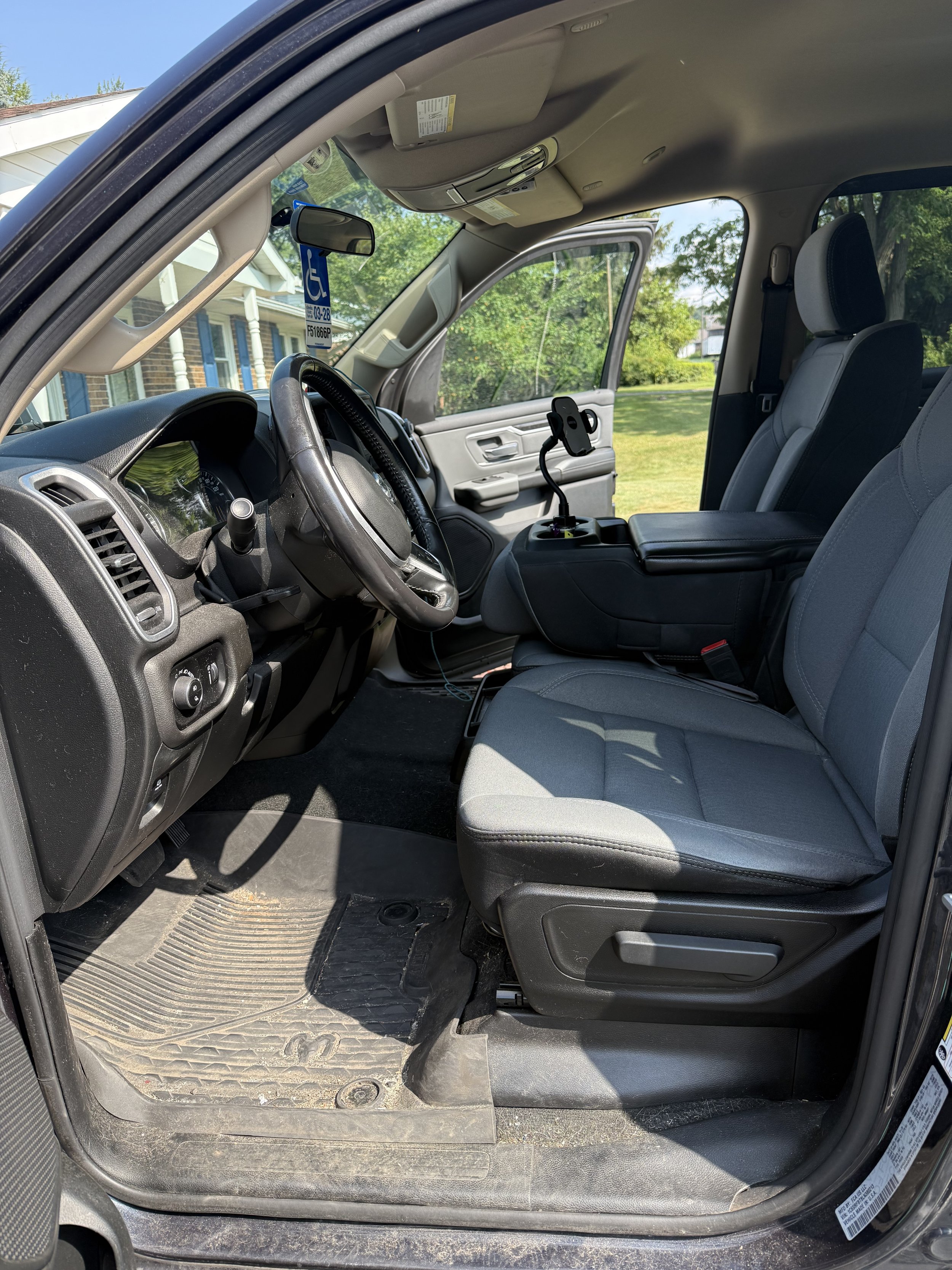 Interior view of a pickup truck's front seats and dashboard, including the steering wheel, gear shift, and a phone holder attached to the center console.