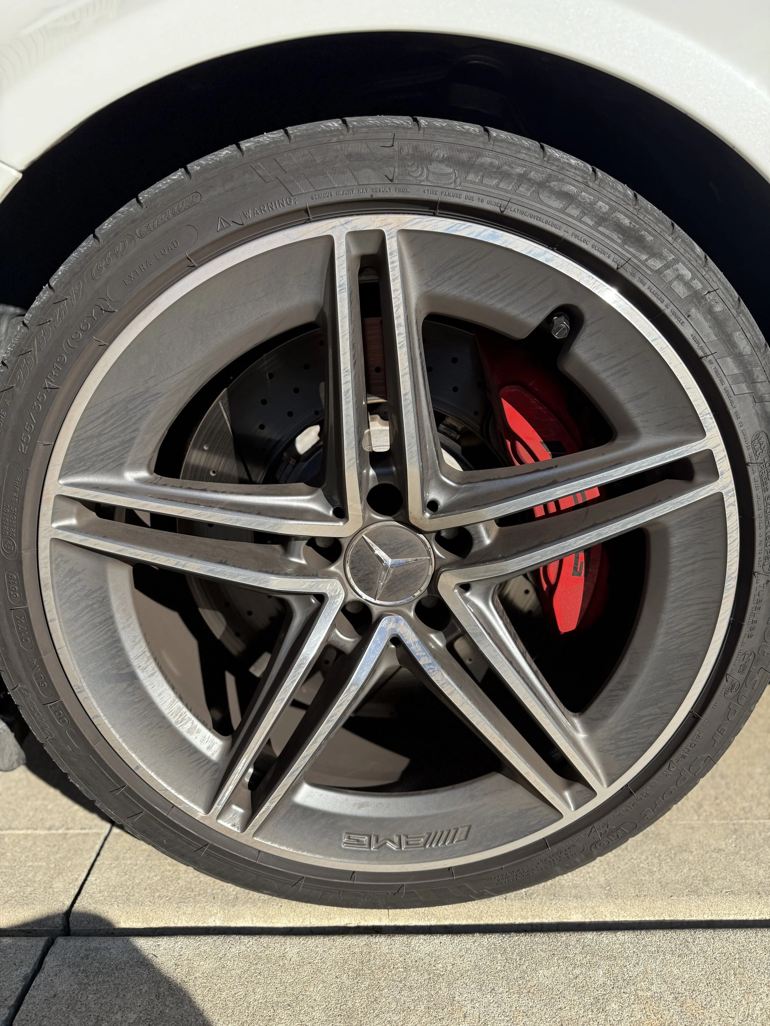 Close-up of a Mercedes-Benz wheel with a silver alloy rim, a red brake caliper, and a black tire.