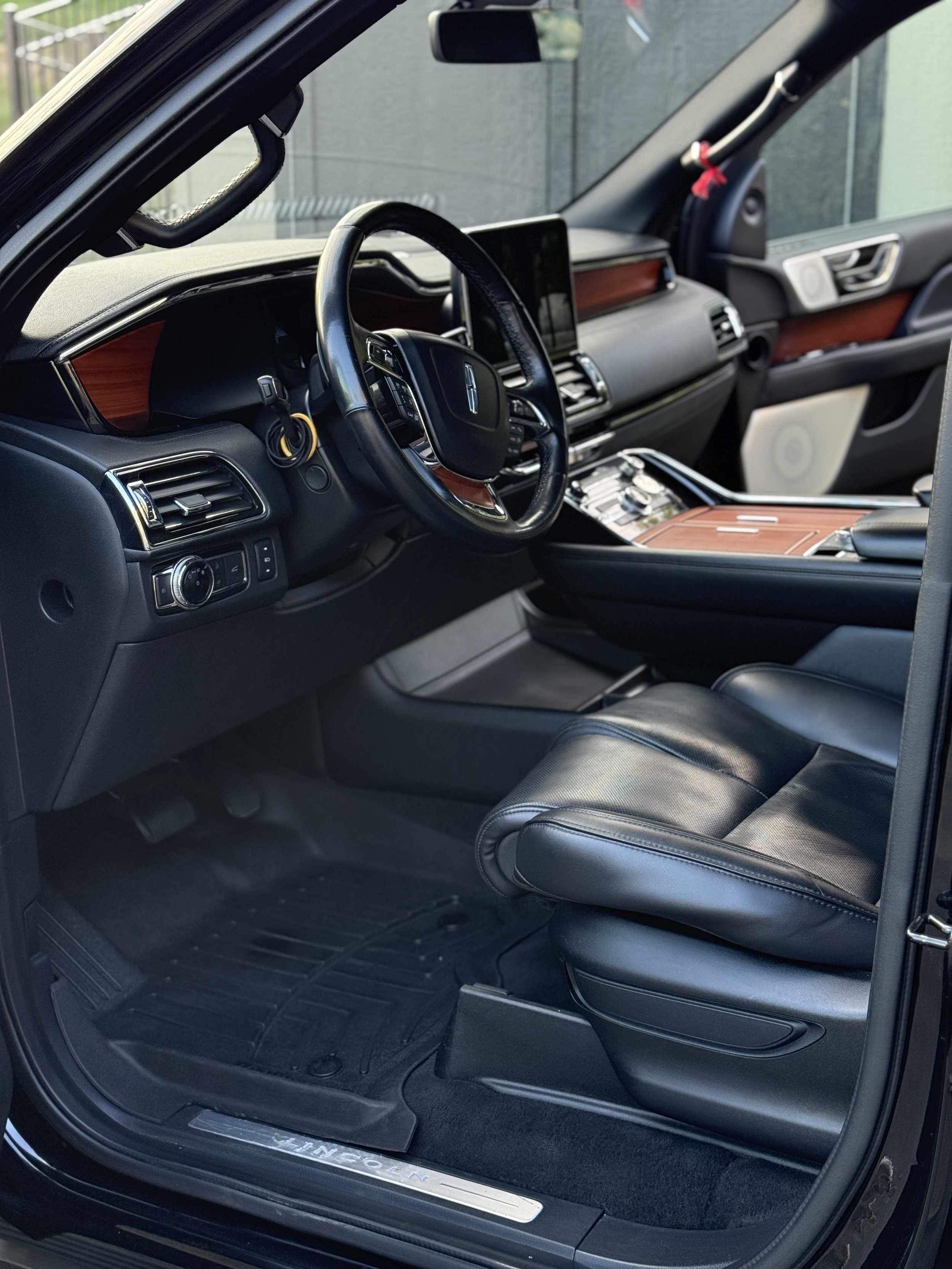 Interior of a luxury vehicle with black leather seats, wooden accents, and a dashboard with a large central screen.