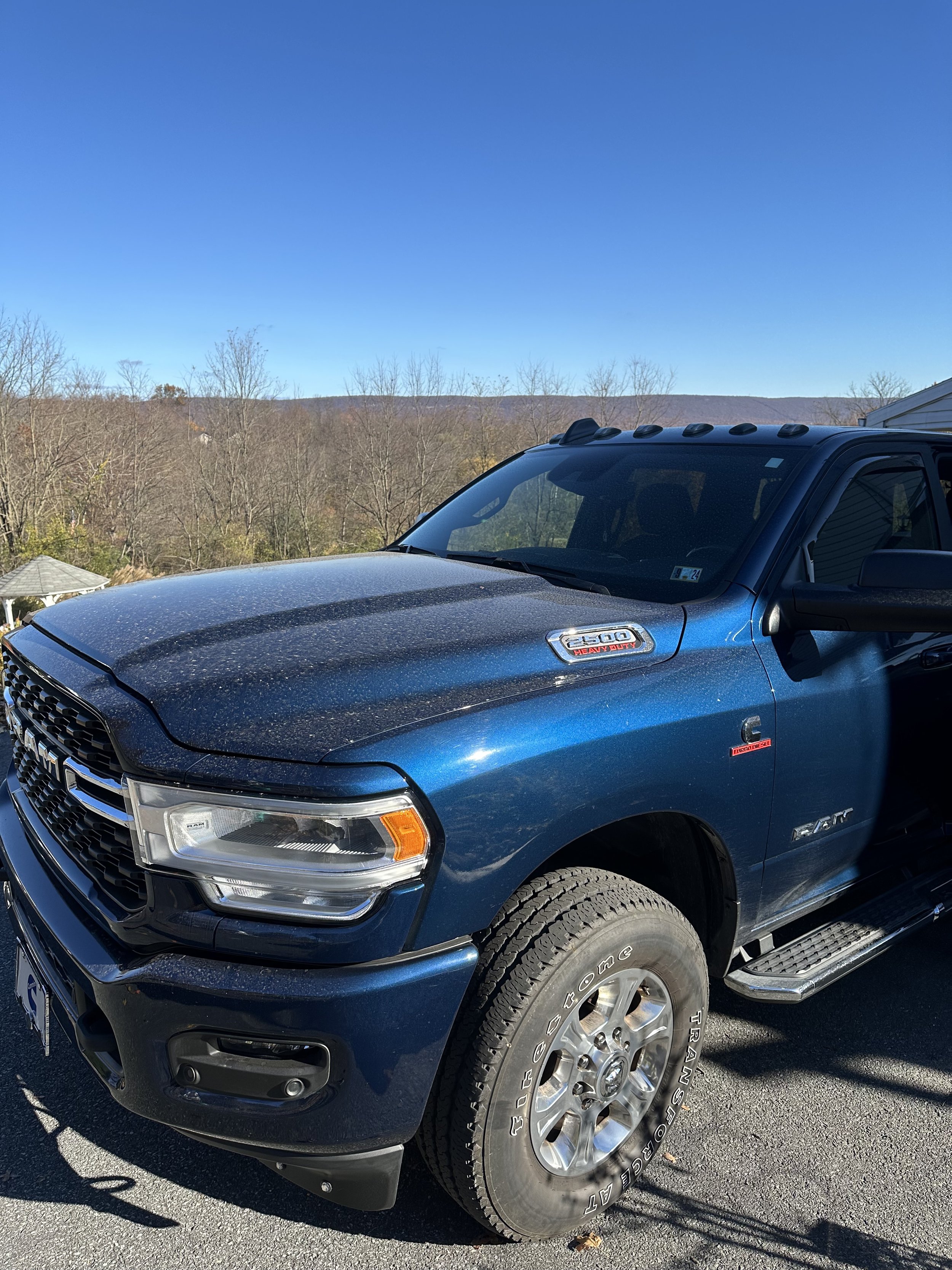 Blue RAM 2500 Heavy Duty pickup truck parked outdoors with a mountain and trees in the background.