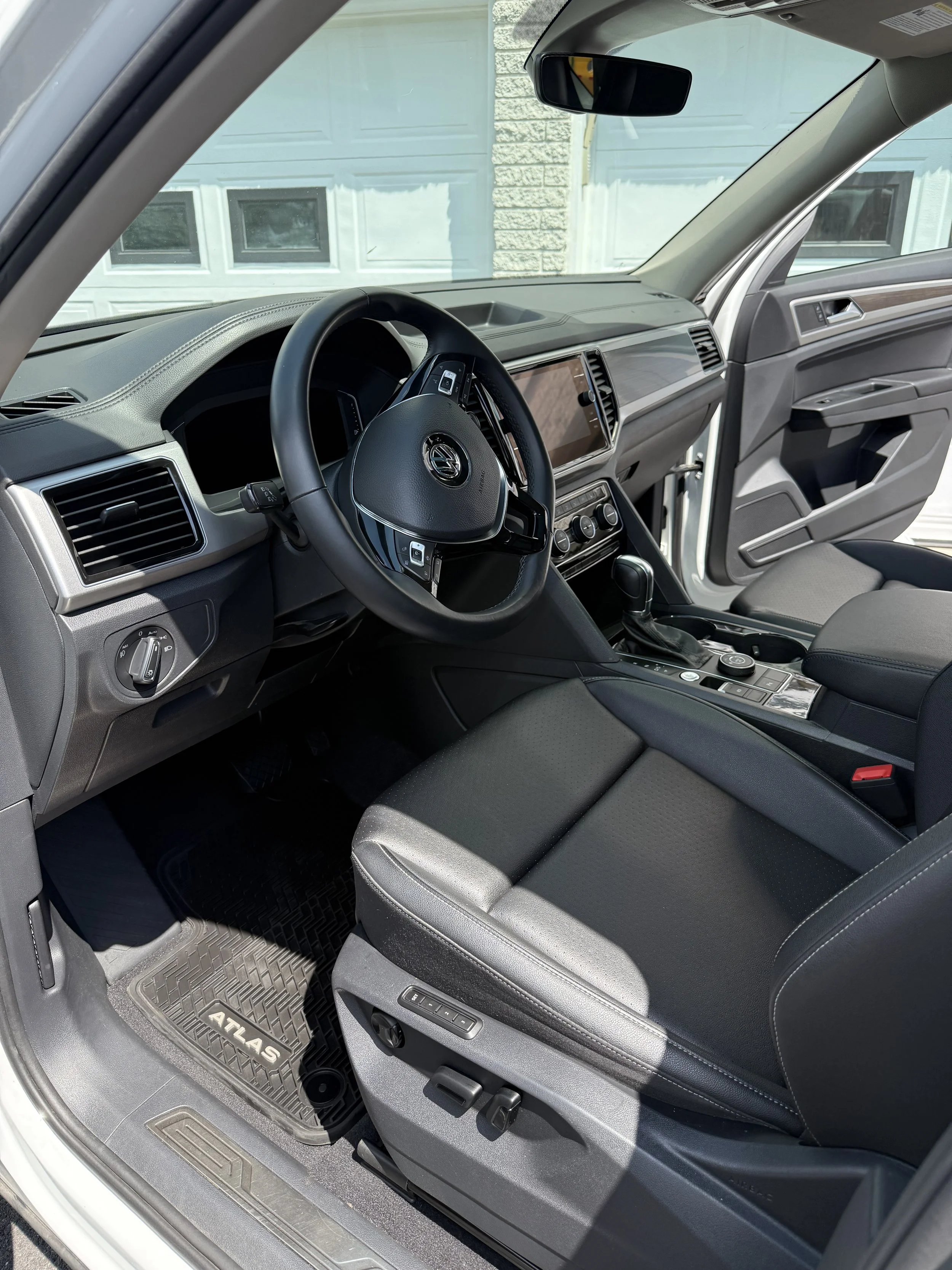 The interior of a Volkswagen Atlas SUV showing the driver's seat, steering wheel, dashboard, and center console.
