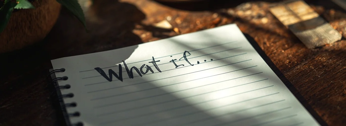 An image of a notepad on a desk with the writing "What if..."