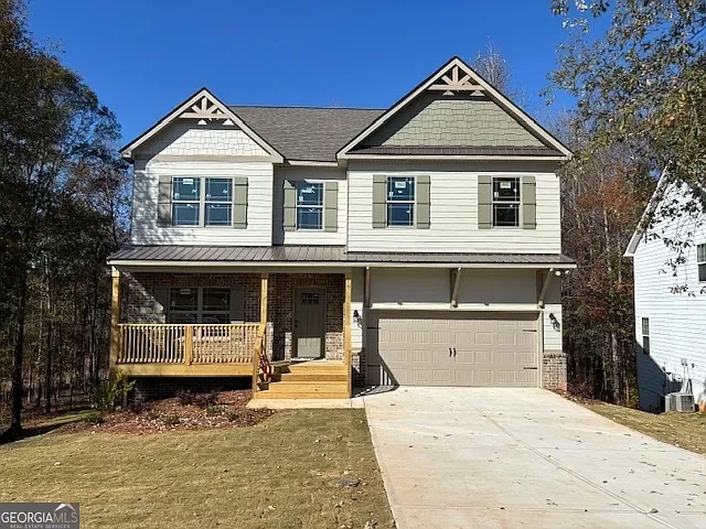 New two-story house with a front porch, attached garage, and a concrete driveway on a clear day.