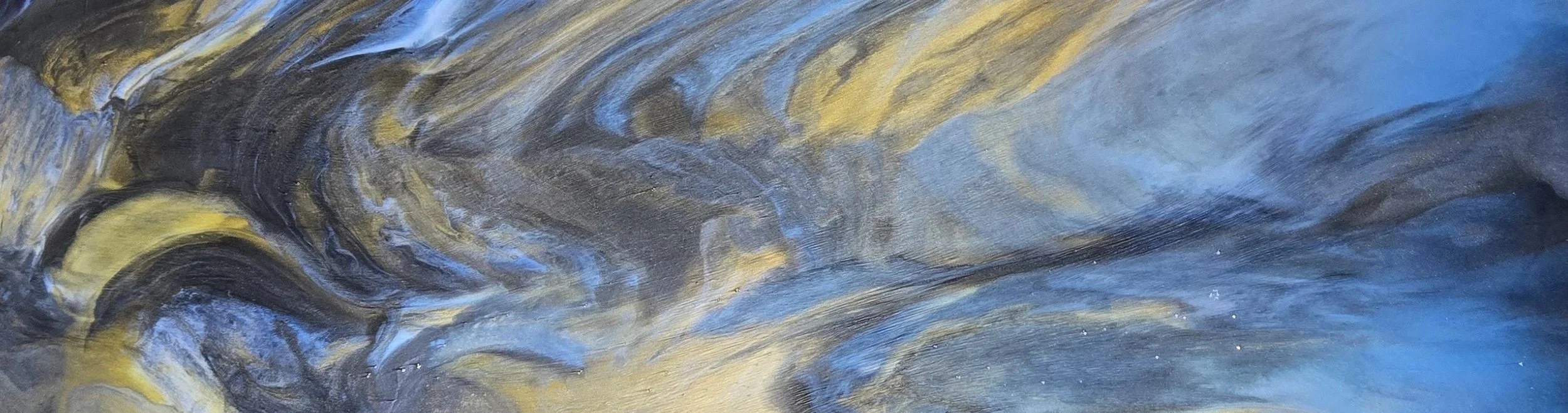 Close-up of a metallic epoxy floor with swirling patterns in shades of black, gray, blue, and yellow.