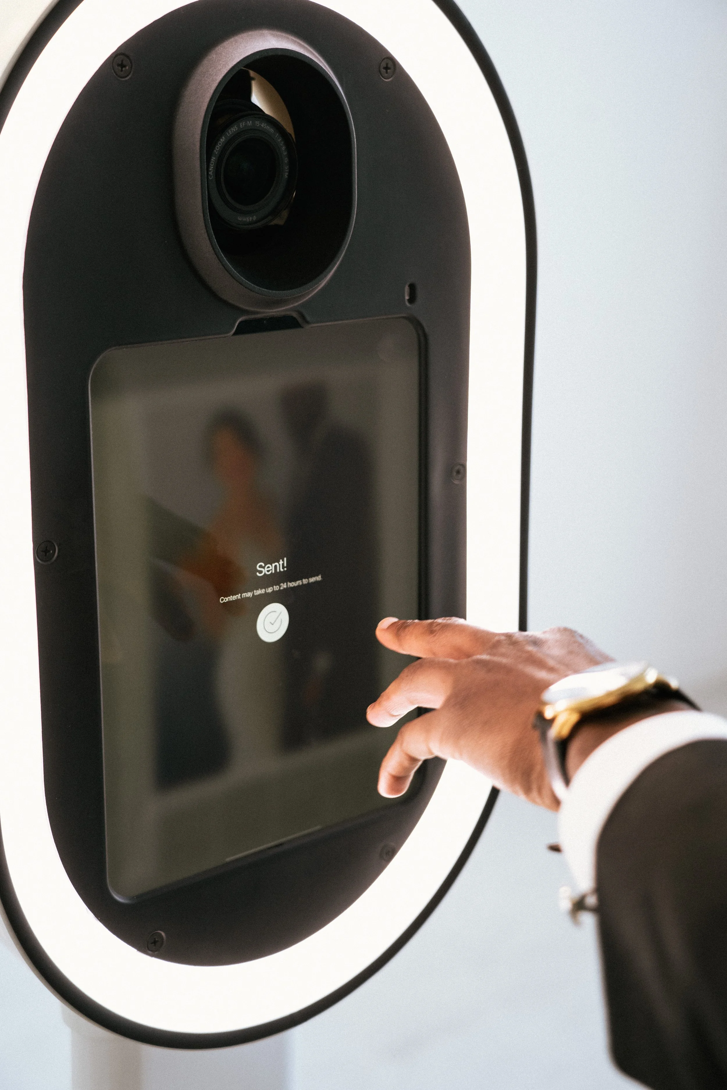 Close-up of a person's hand pressing a touchscreen on a postal kiosk, with a message indicating the mail has been sent.
