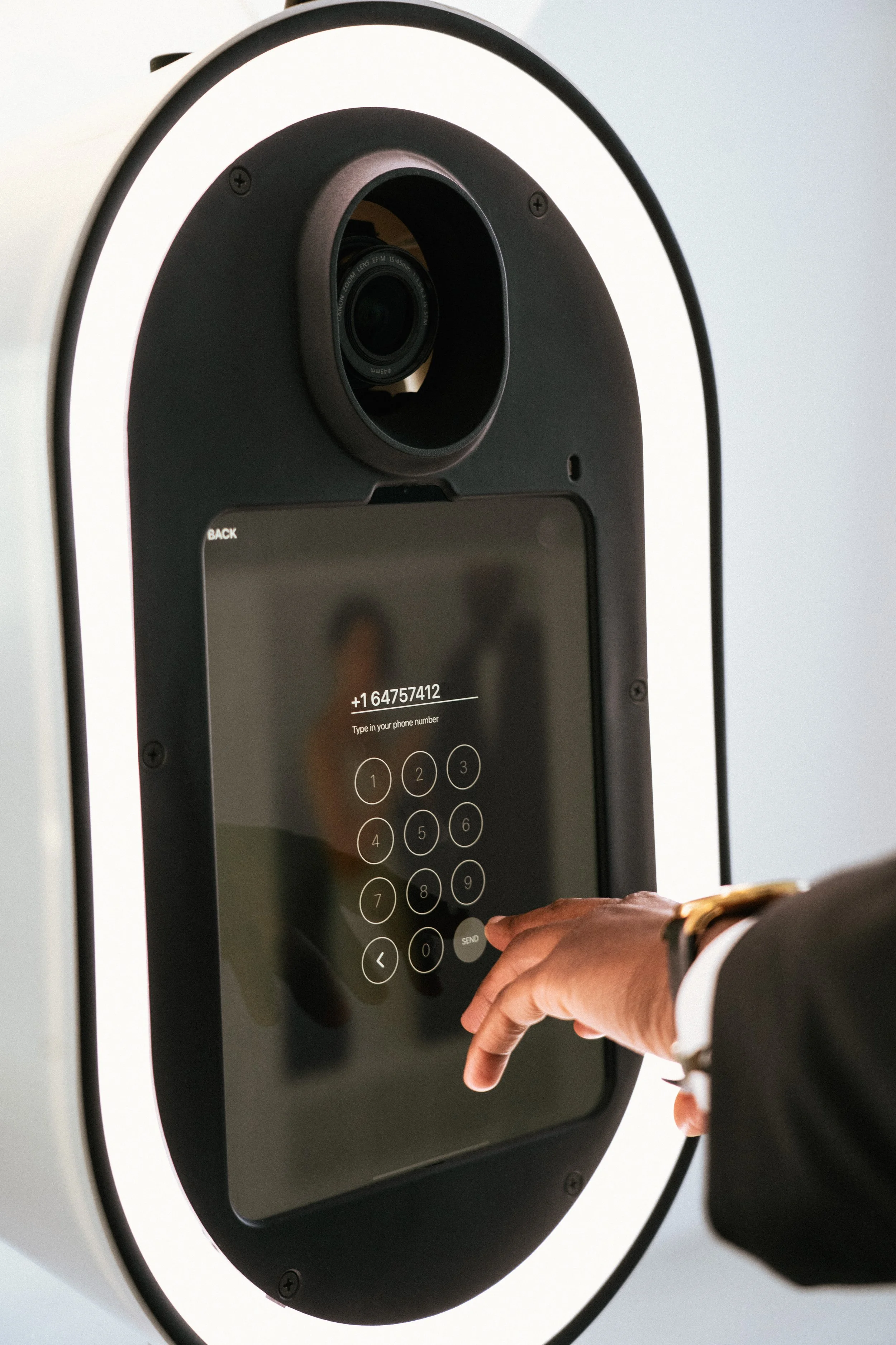 A person in a suit using a touchscreen kiosk to dial a phone number.