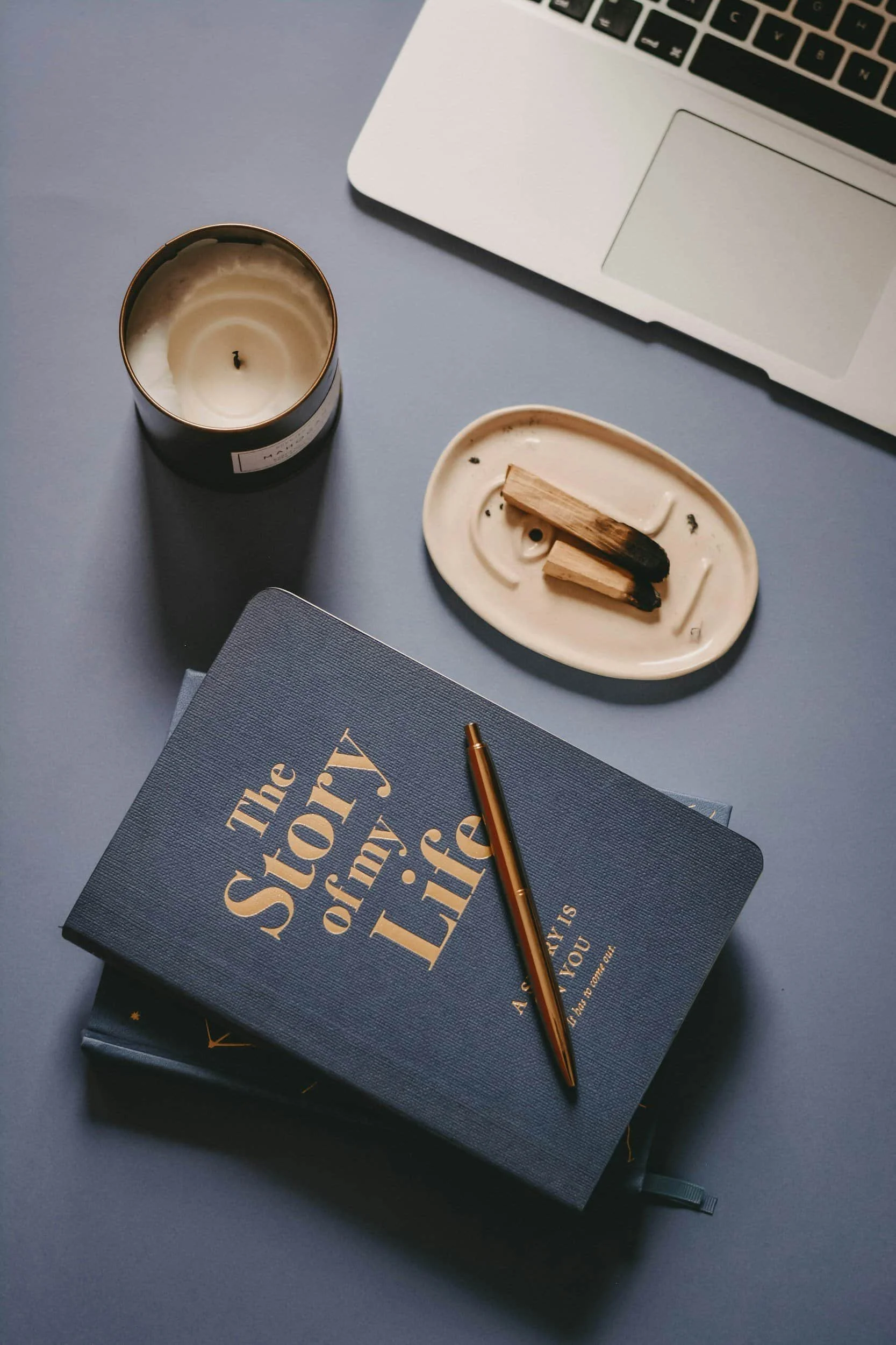 Black journal with modern gold print and pen resting atop a black desk.