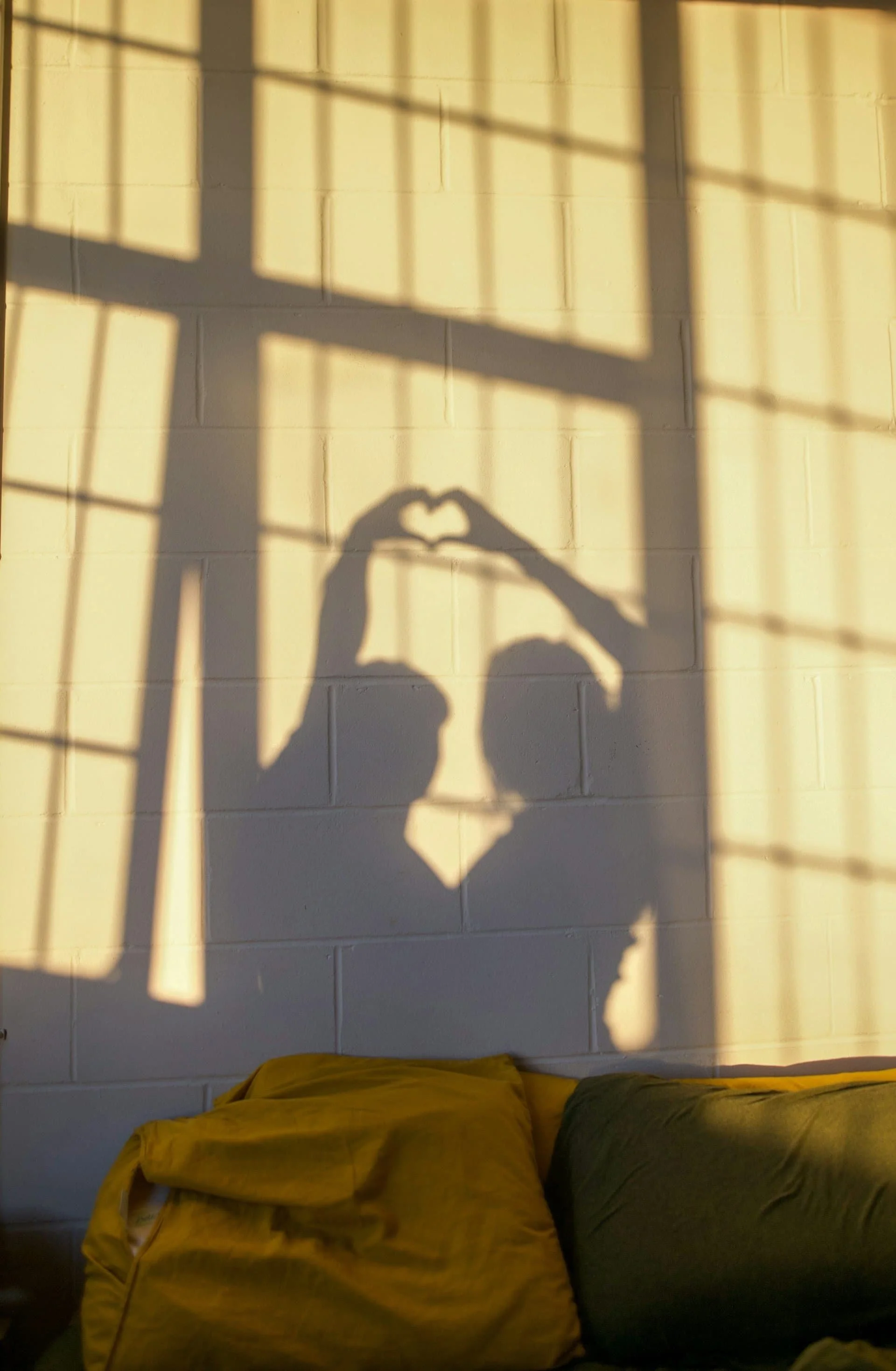 Silhouette of young couple making heart hands and enjoying a tender moment.