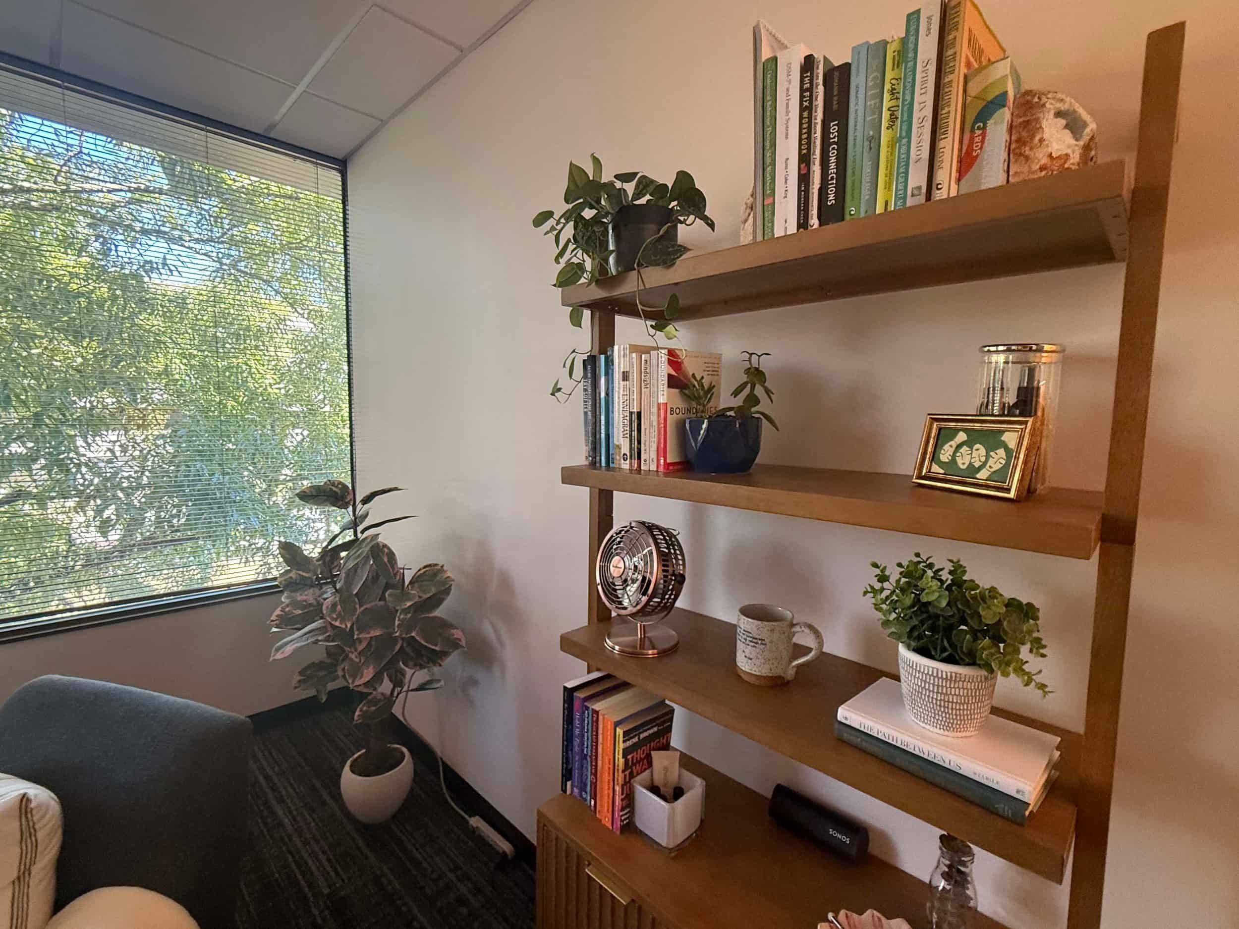 Afternoon light pouring into a therapy office filled with plants and inspiring books.