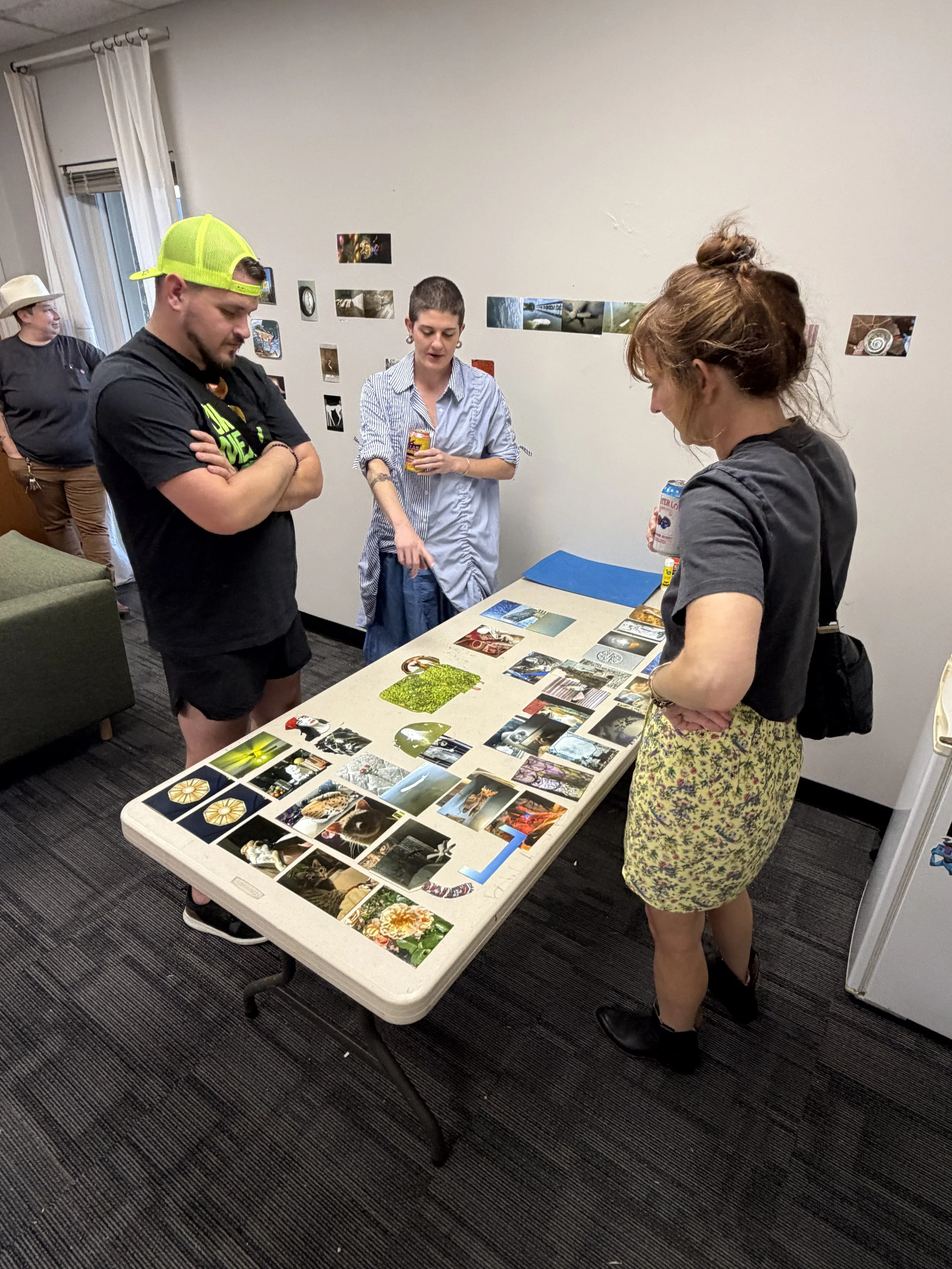Max Marshall points to a table of cut photos as two visitors look on