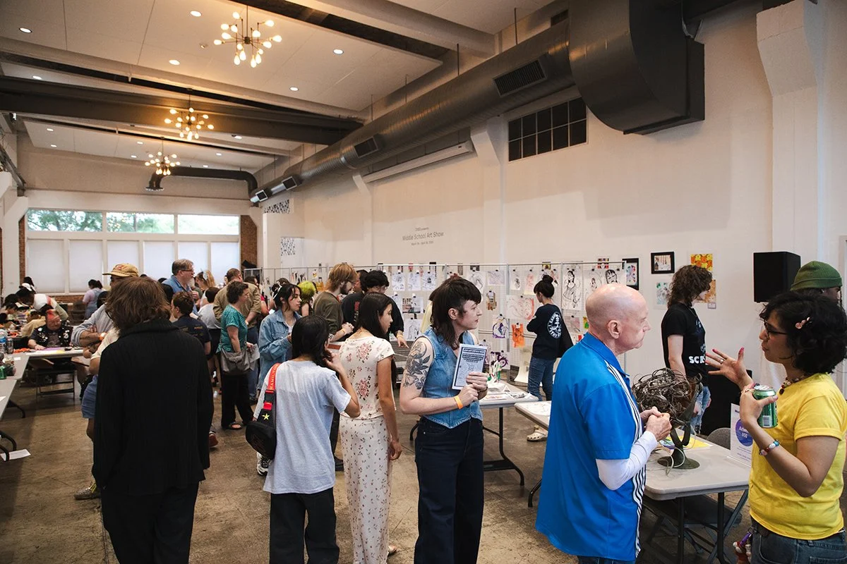 hundreds of people fill Festival Hall at Greater Denton Arts Council talking to art collectives and watching artist make art live at Monster Art Rally