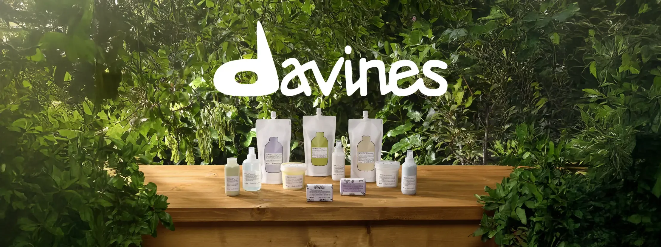 Display of skincare and personal care products on a wooden table with a lush green leafy background and the word 'daviess' in large white text above.
