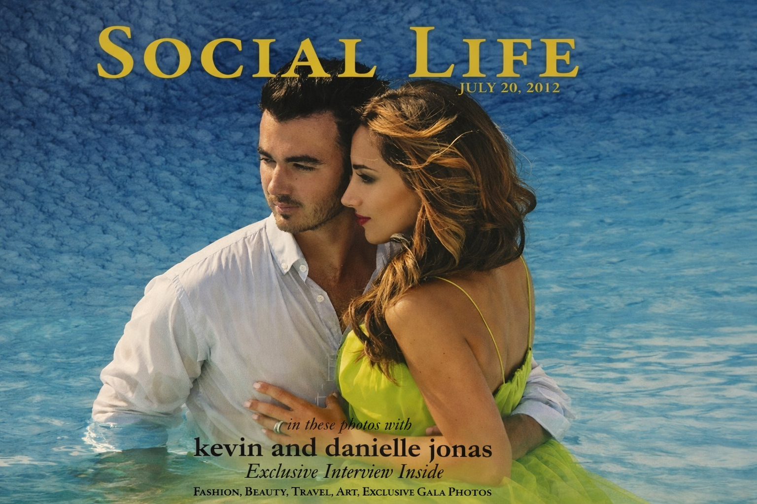 A man and woman standing indoors, looking upward, with the woman holding her hands together, in front of a decorative iron gate.