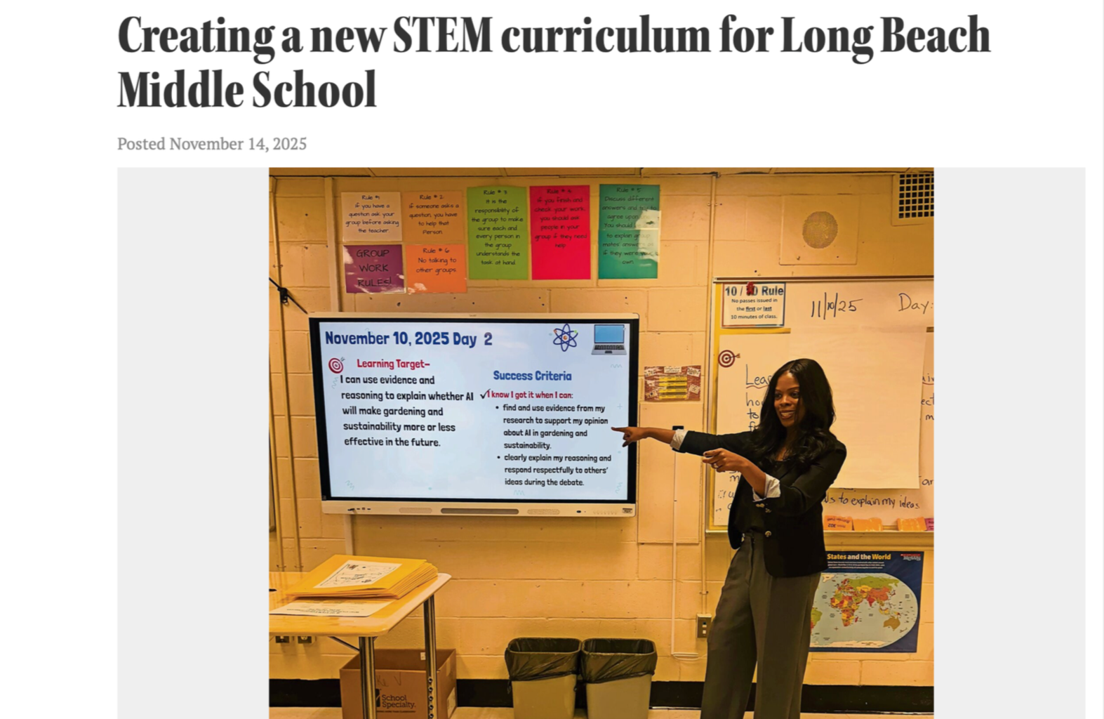 A woman standing in a classroom, pointing to a digital display on the wall that shows an educational slide titled 'November 10, 2025, Day 2', with learning targets and success criteria about evidence, reasoning, and sustainability in gardening.