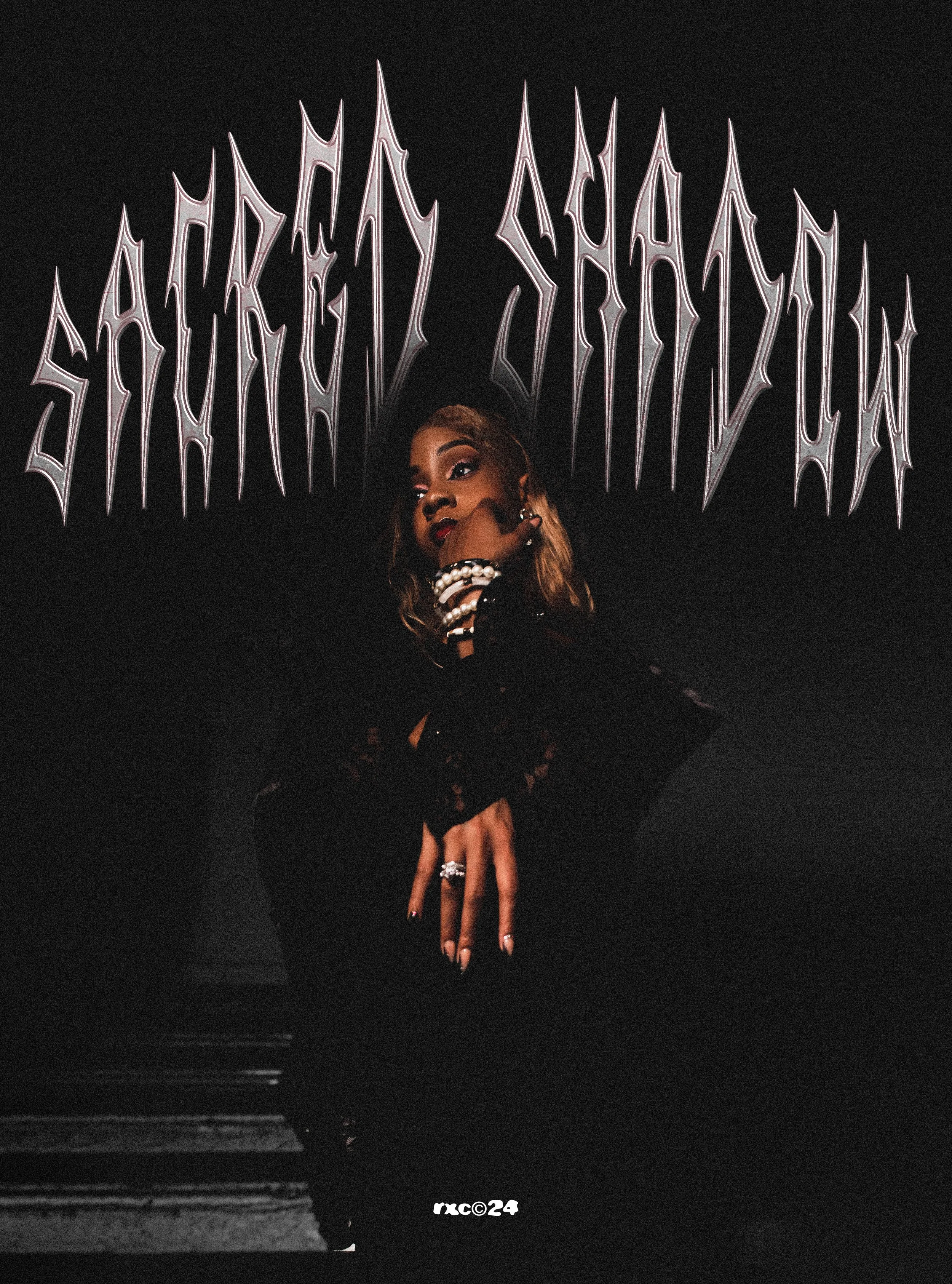 A woman with long hair, dark lipstick, and jewelry, wearing black lace gloves, posing with her hand near her face in front of a black background. Above her, stylized text reads 'SACREDLY SHY YACHT', and at the bottom, there is small white text 'rxc©24'.