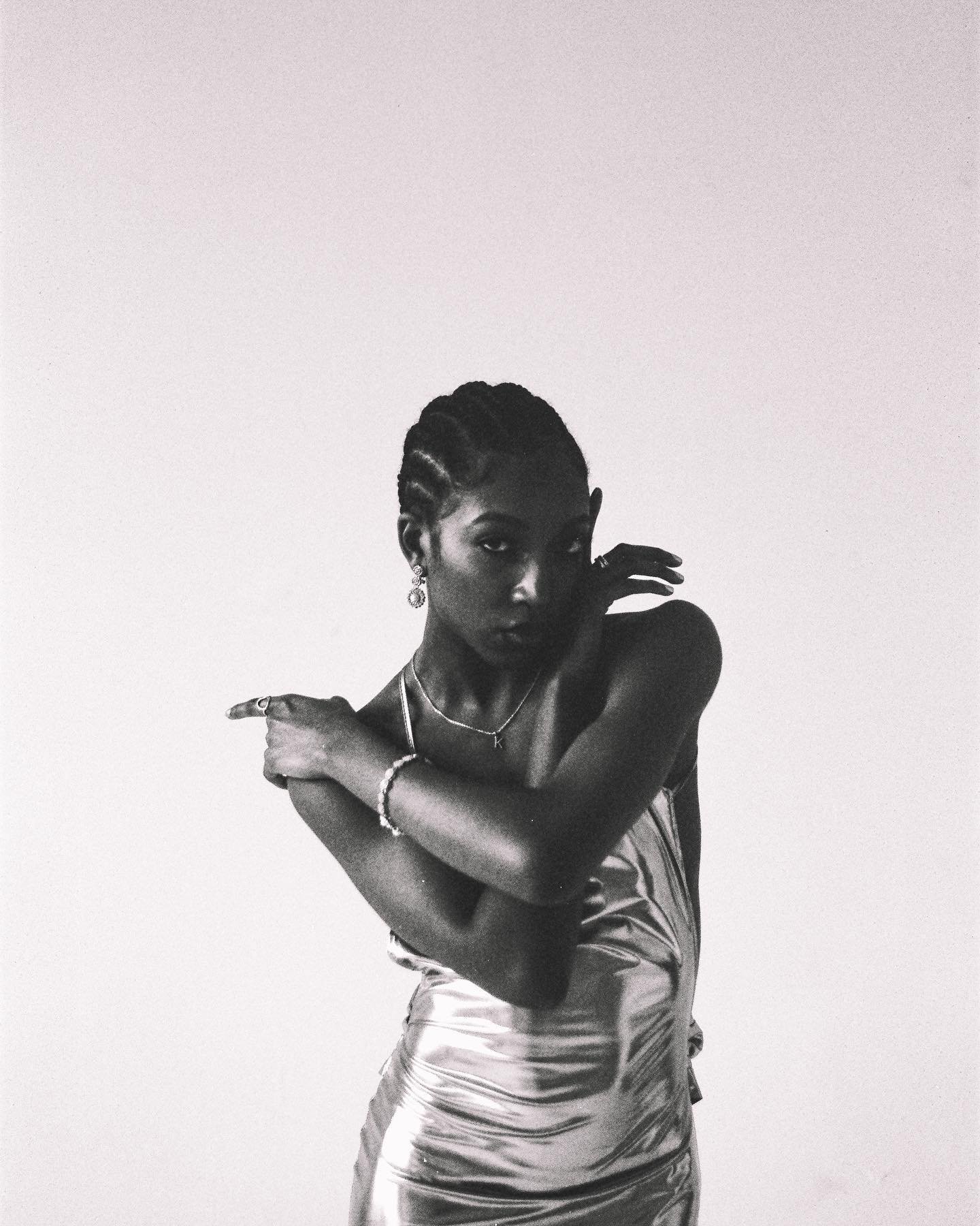 Black woman with braided hair and jewelry posing against a plain white background.