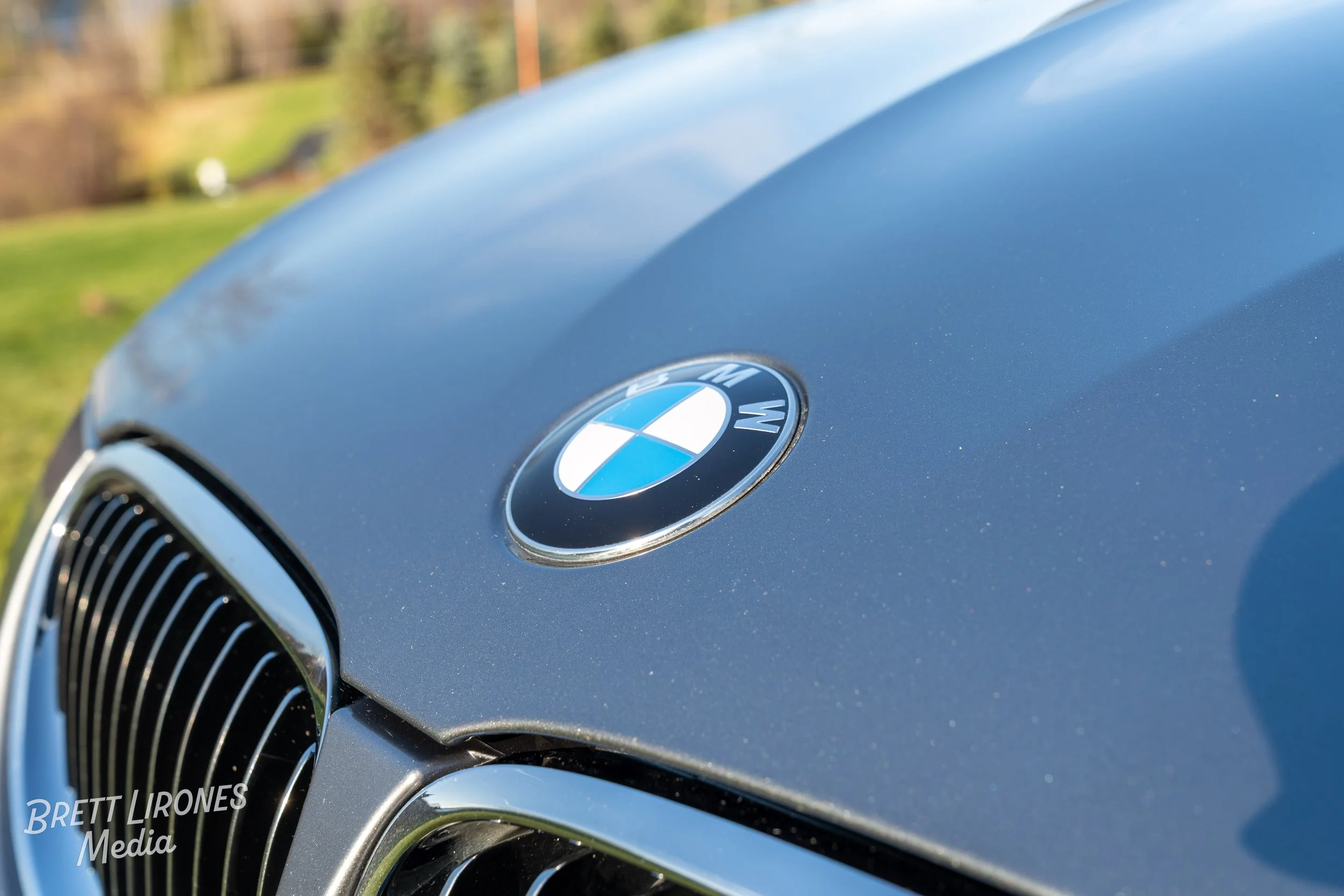 Close-up of a blue BMW car's front grille and hood with the BMW logo.