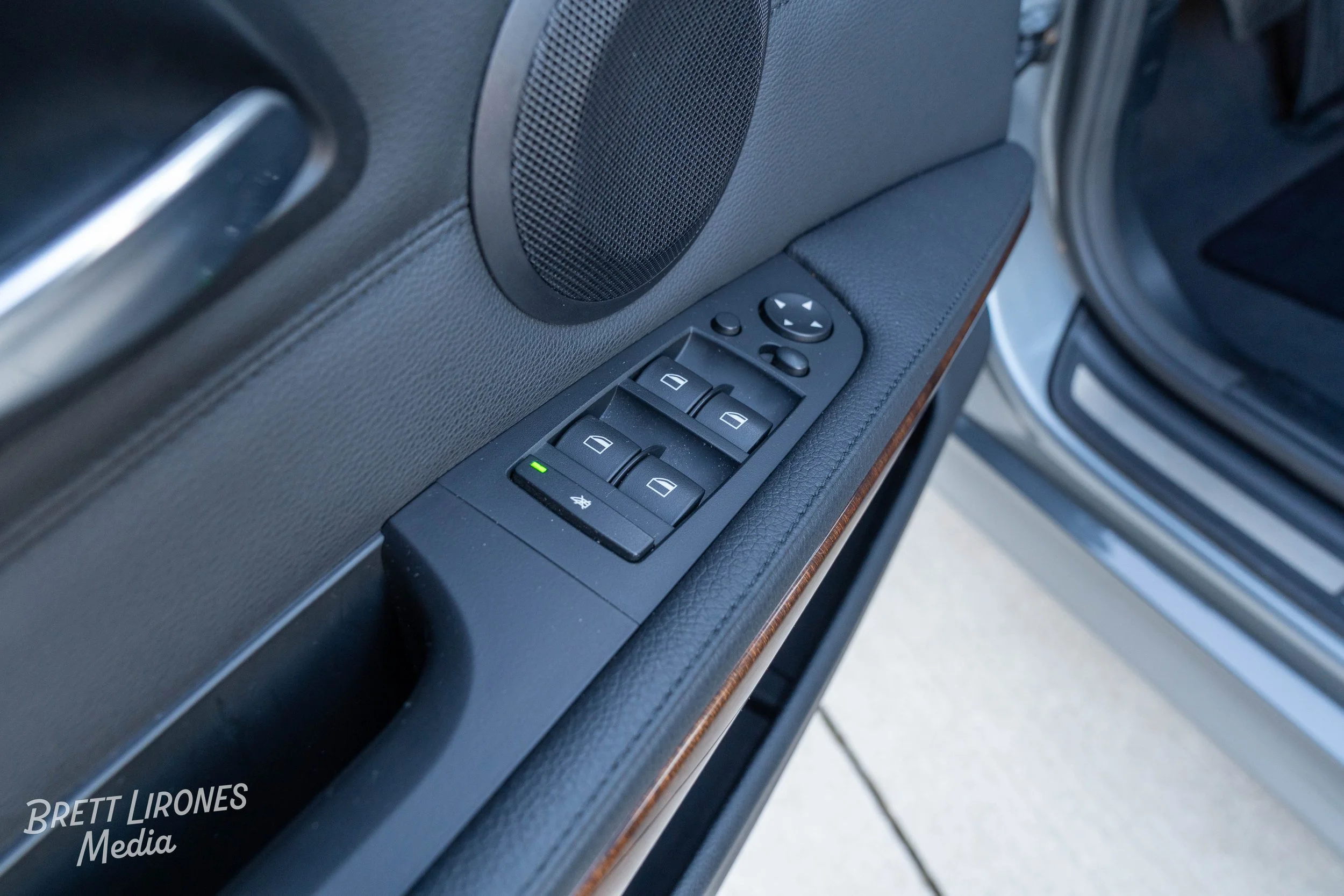 Close-up of a car door's control panel with window buttons, lock button, and side mirror adjustment knob.
