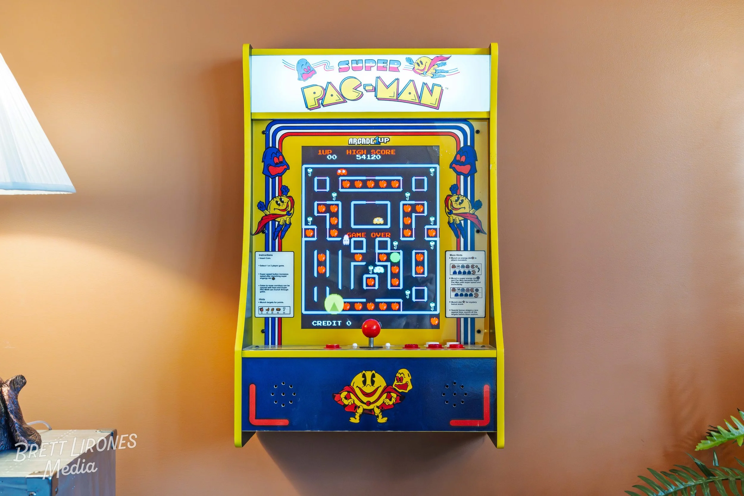 Pac-Man arcade game machine with colorful graphics and characters, displayed against a peach-colored wall.