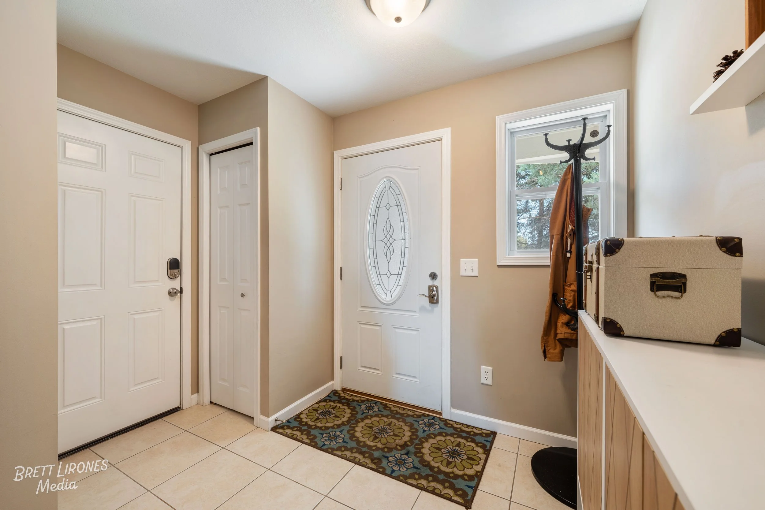 Entryway with a white door, window, coat rack, and a box on a shelf