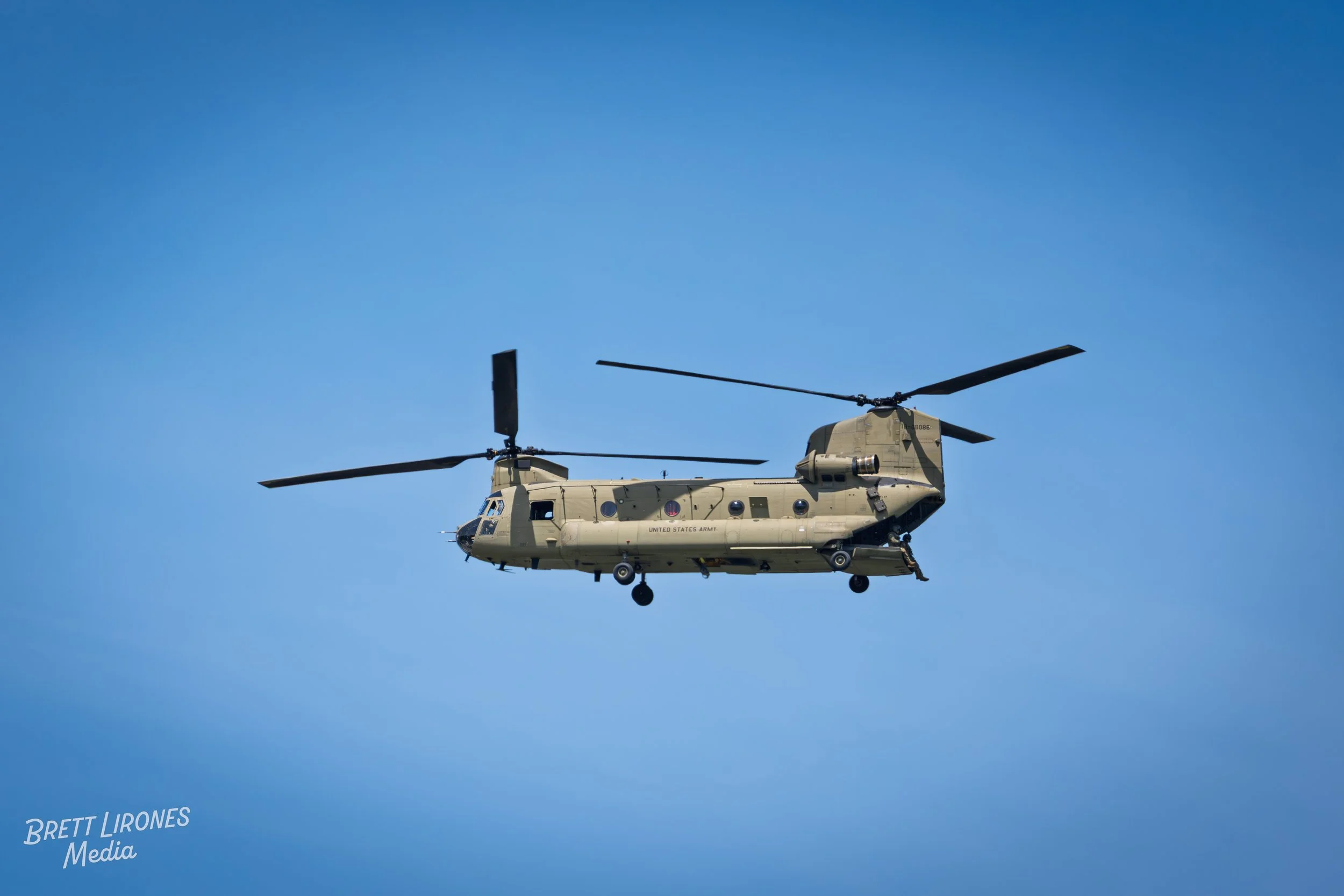 A military helicopter flying in a clear blue sky.