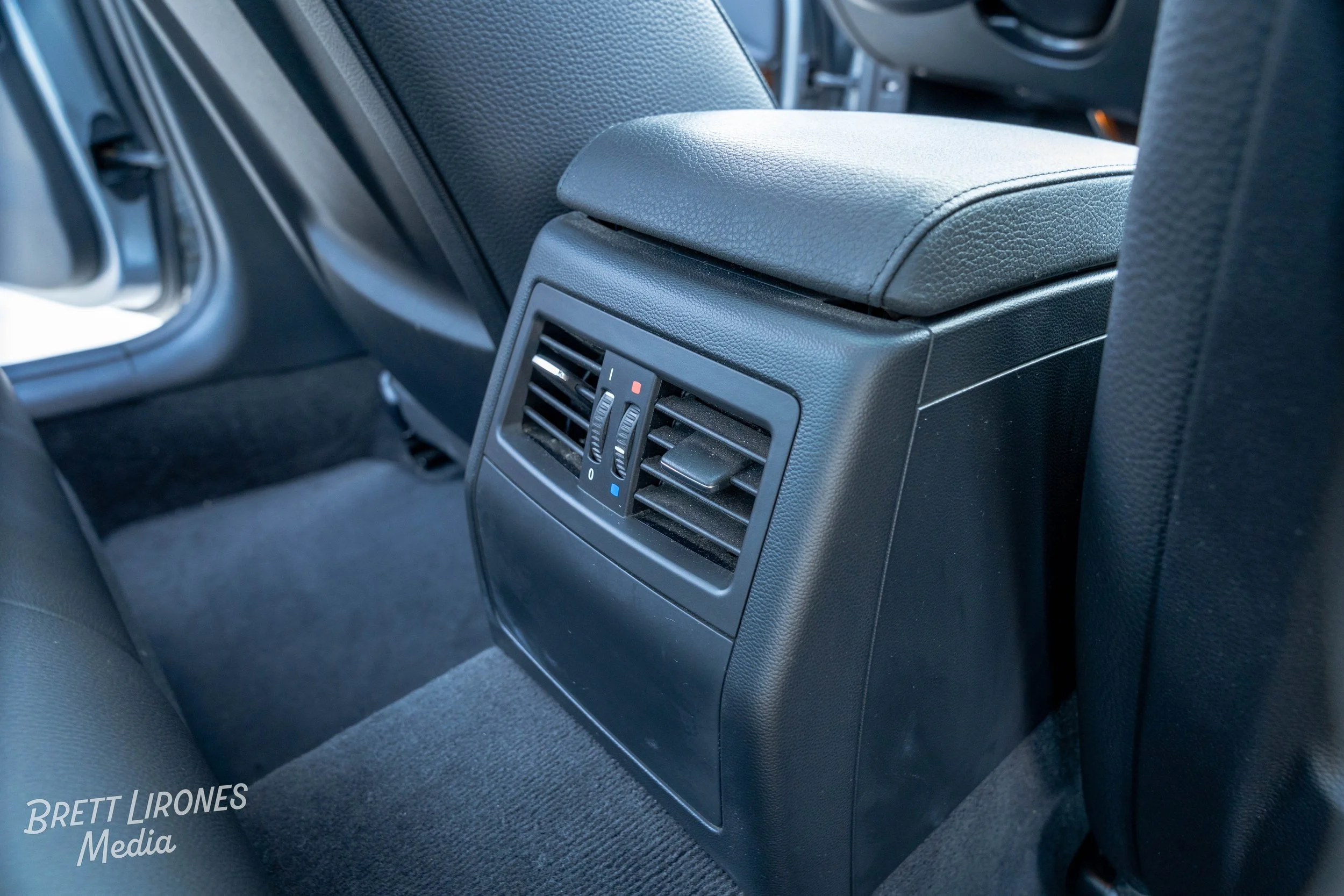 The backseat of a car showing a rear air vent with adjustable louvers and temperature control switches.