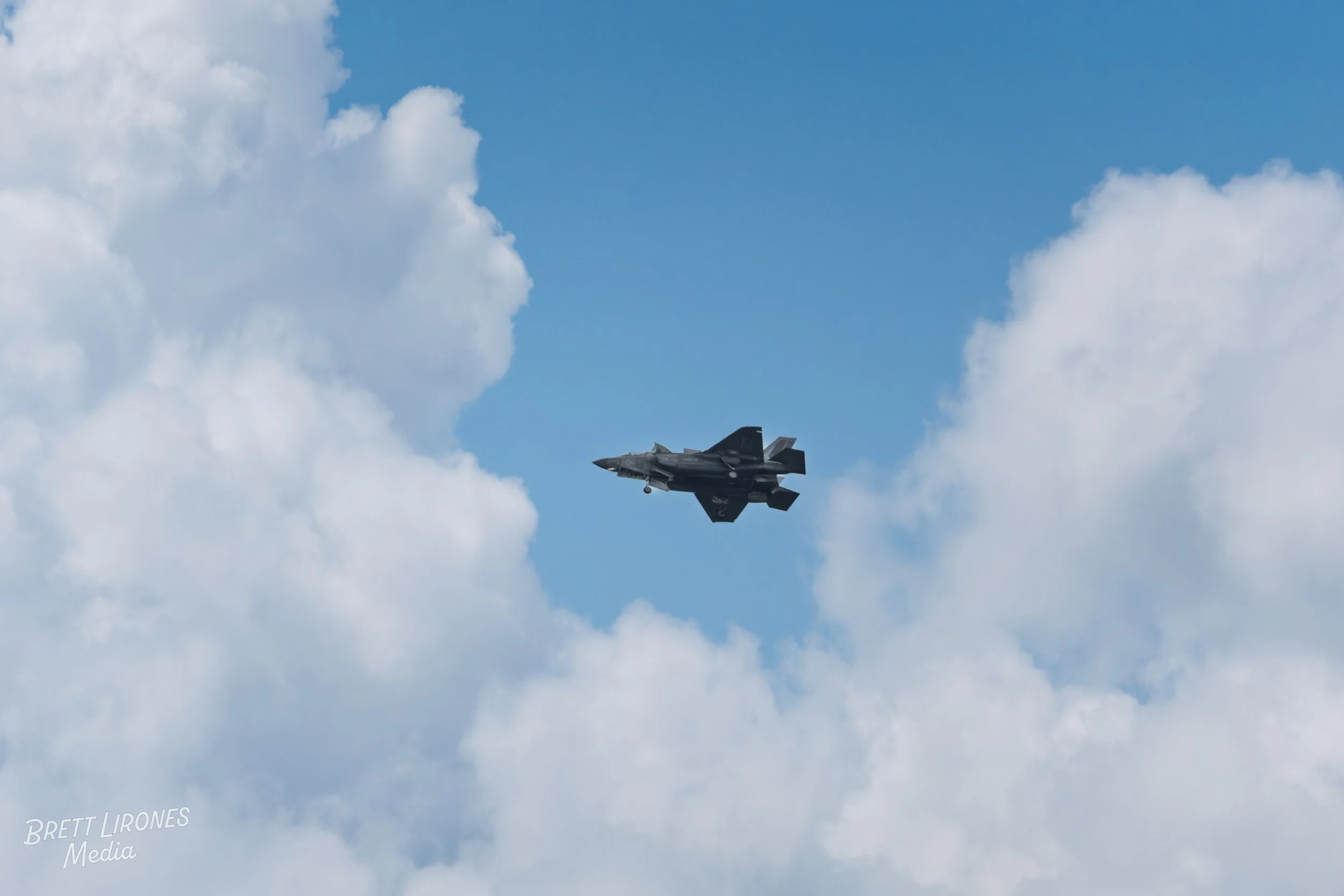 A fighter jet flying through a partly cloudy sky.