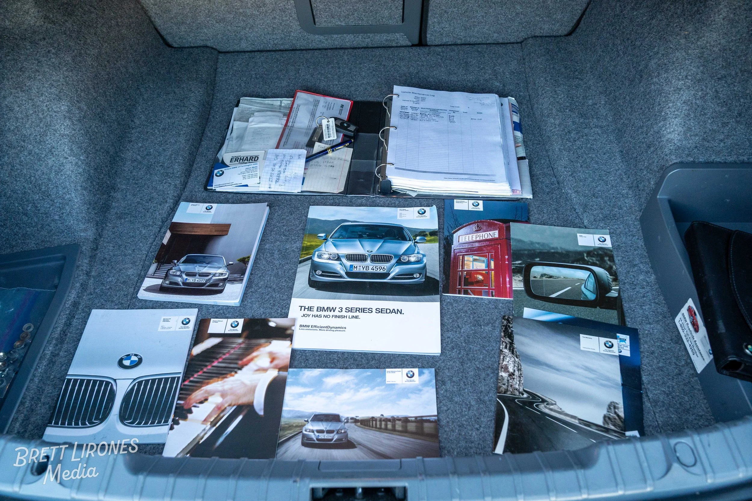 Car documents and brochures laid out in the trunk of a vehicle.
