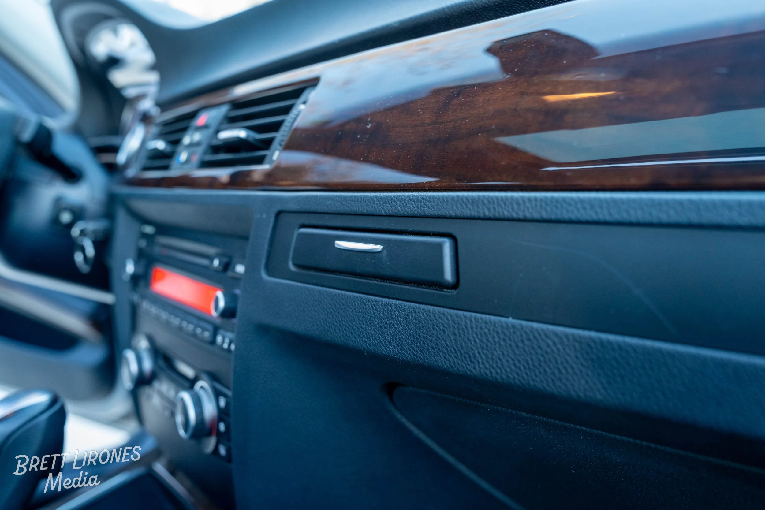 Close-up of a car dashboard with wood trim and climate control panel.
