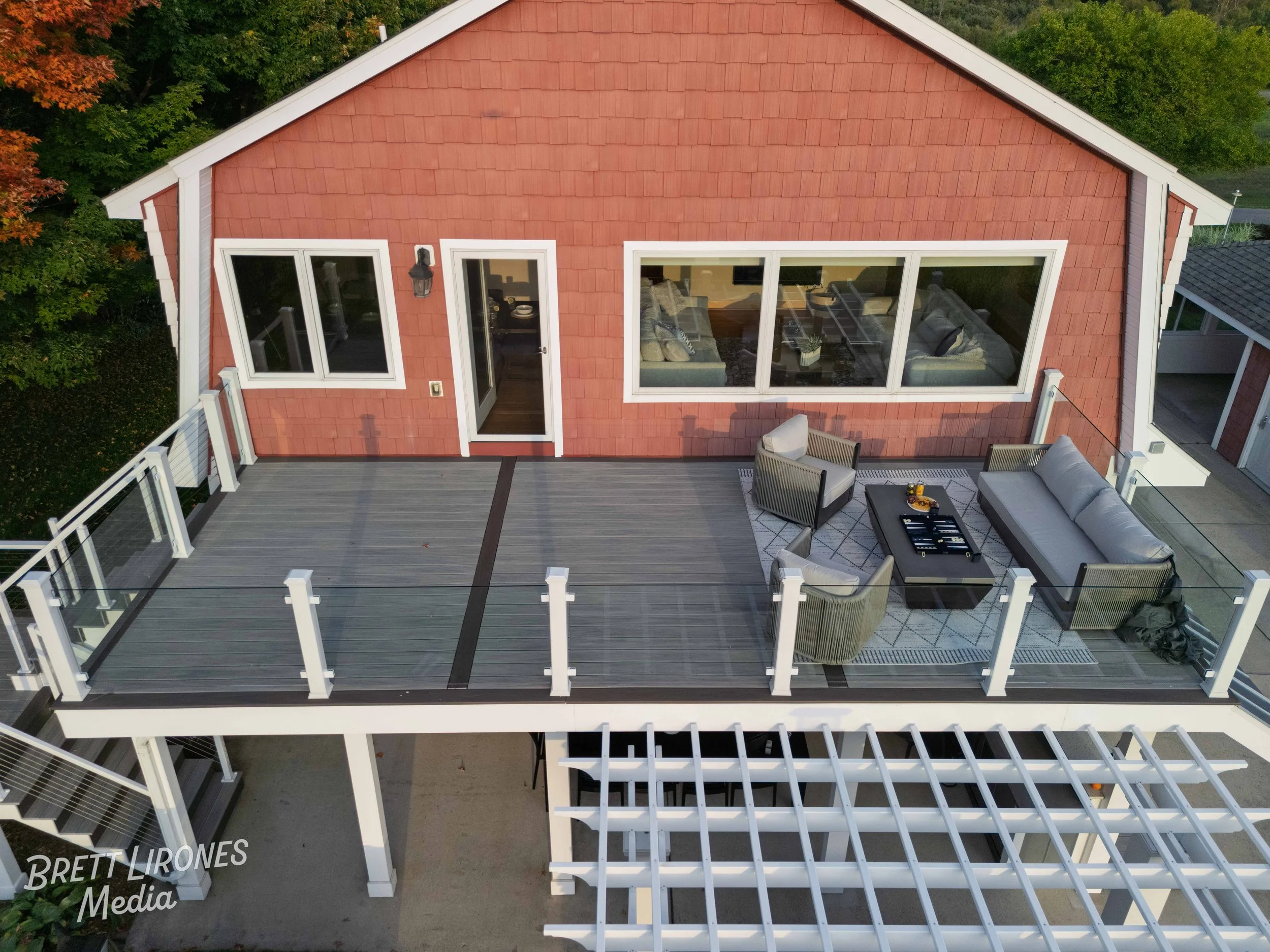Aerial view of a house's outdoor deck with seating, overlooking lush green trees.