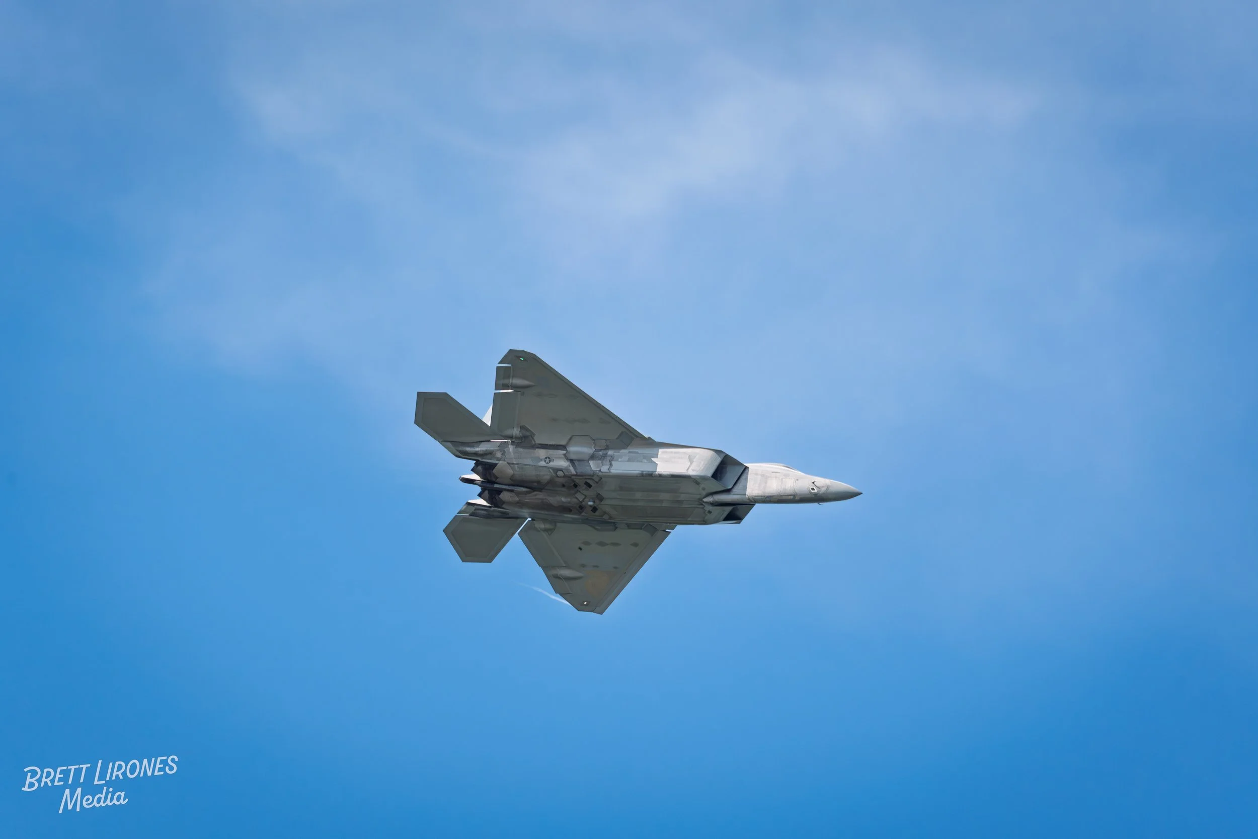 A stealth fighter jet flying in a clear blue sky.
