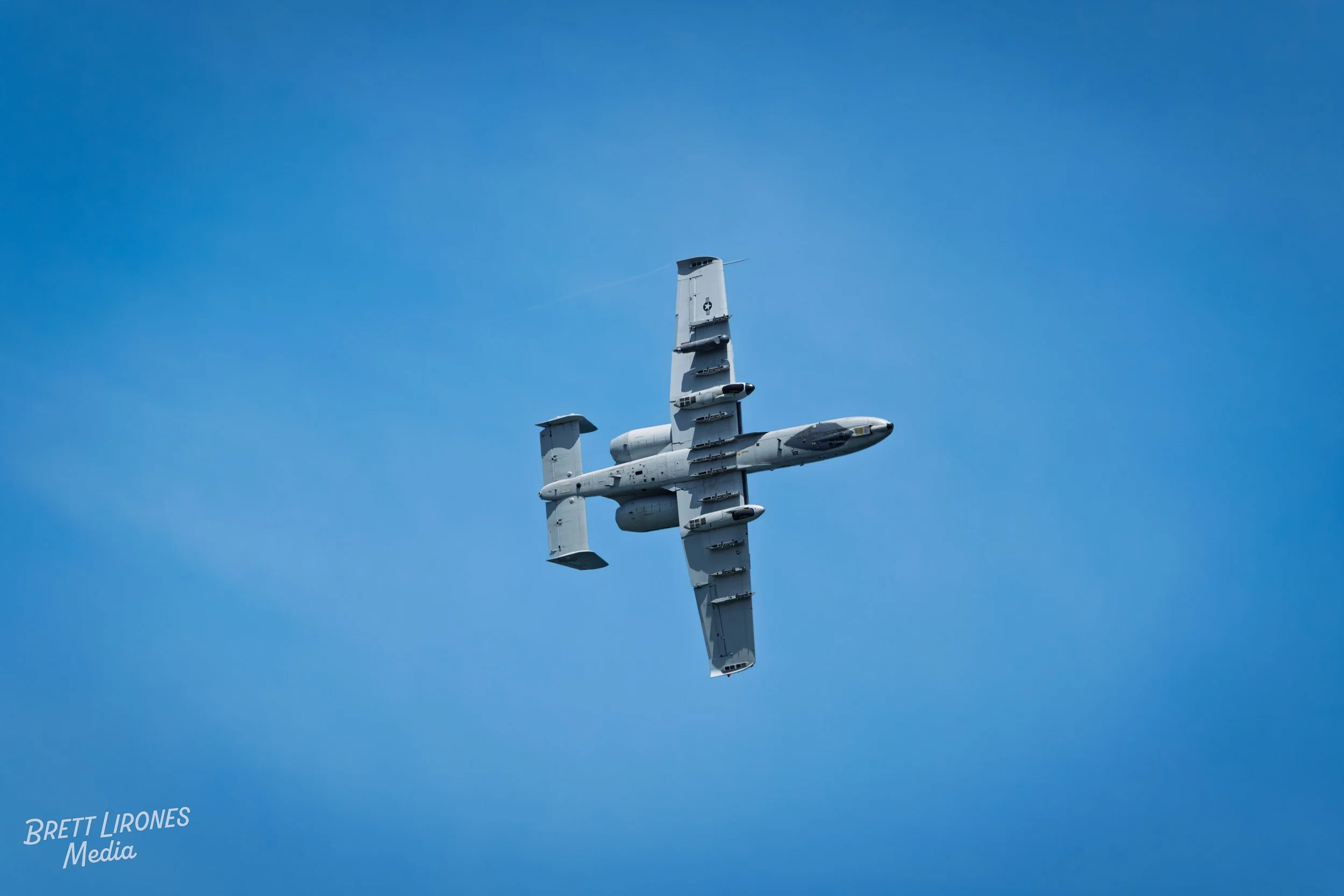 A military aircraft flying in a clear blue sky.