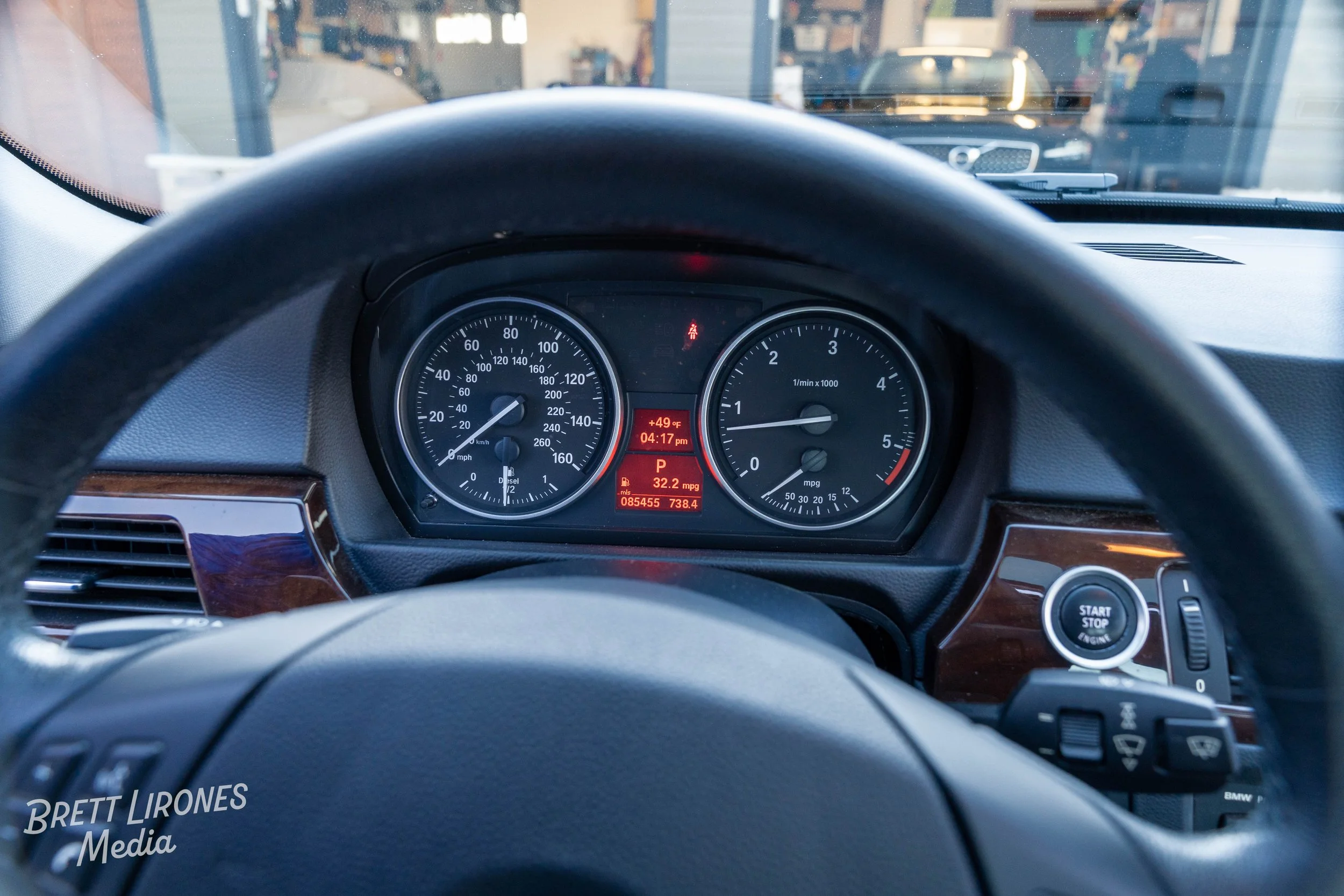 The interior of a car, showing the dashboard and steering wheel, with the speedometer and tachometer, and a digital display indicating a temperature of 49°F, a time of 4:17 pm, and a fuel efficiency of 32.2 mpg.
