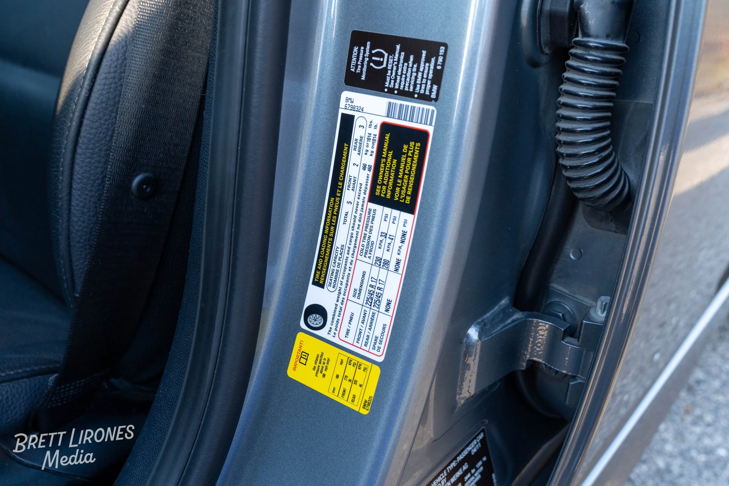 A vehicle's door frame with various tire and loading information labels, including tire pressure recommendations and manufacturing details.