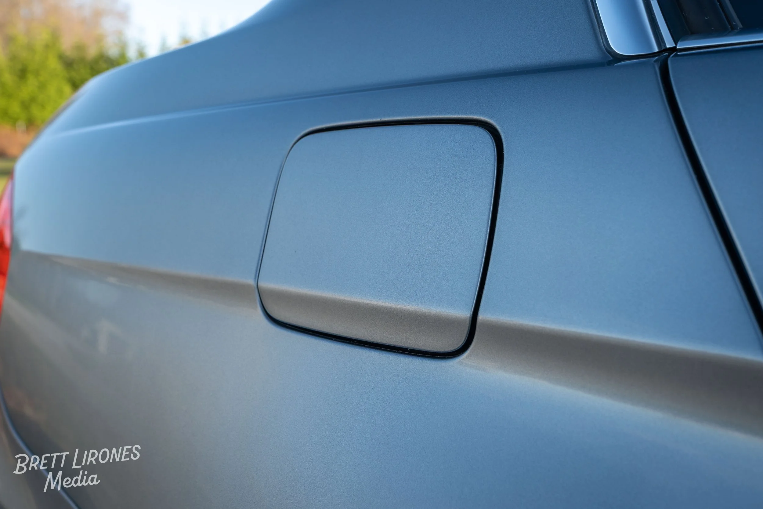 Close-up of a silver car's fuel door on the side of the vehicle.