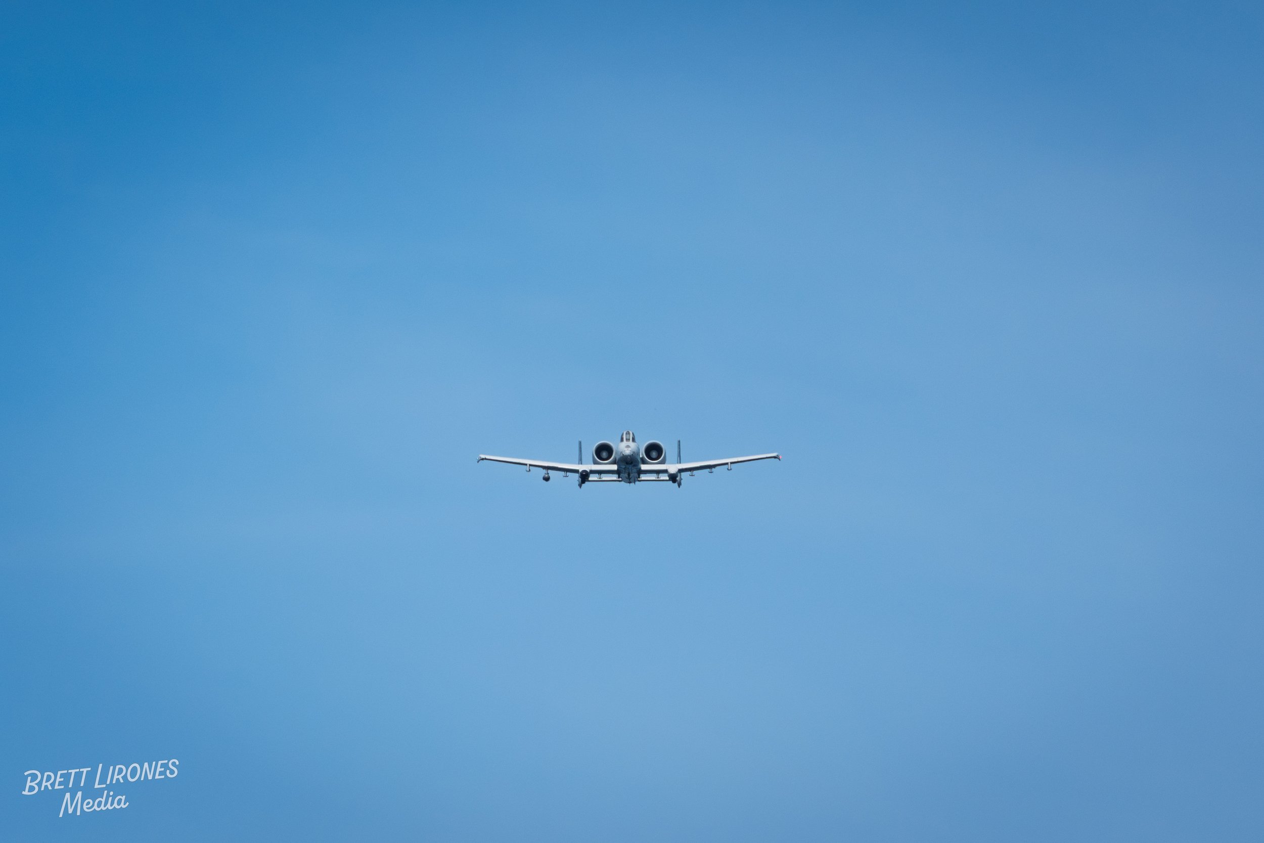 A military jet flying in the clear blue sky.