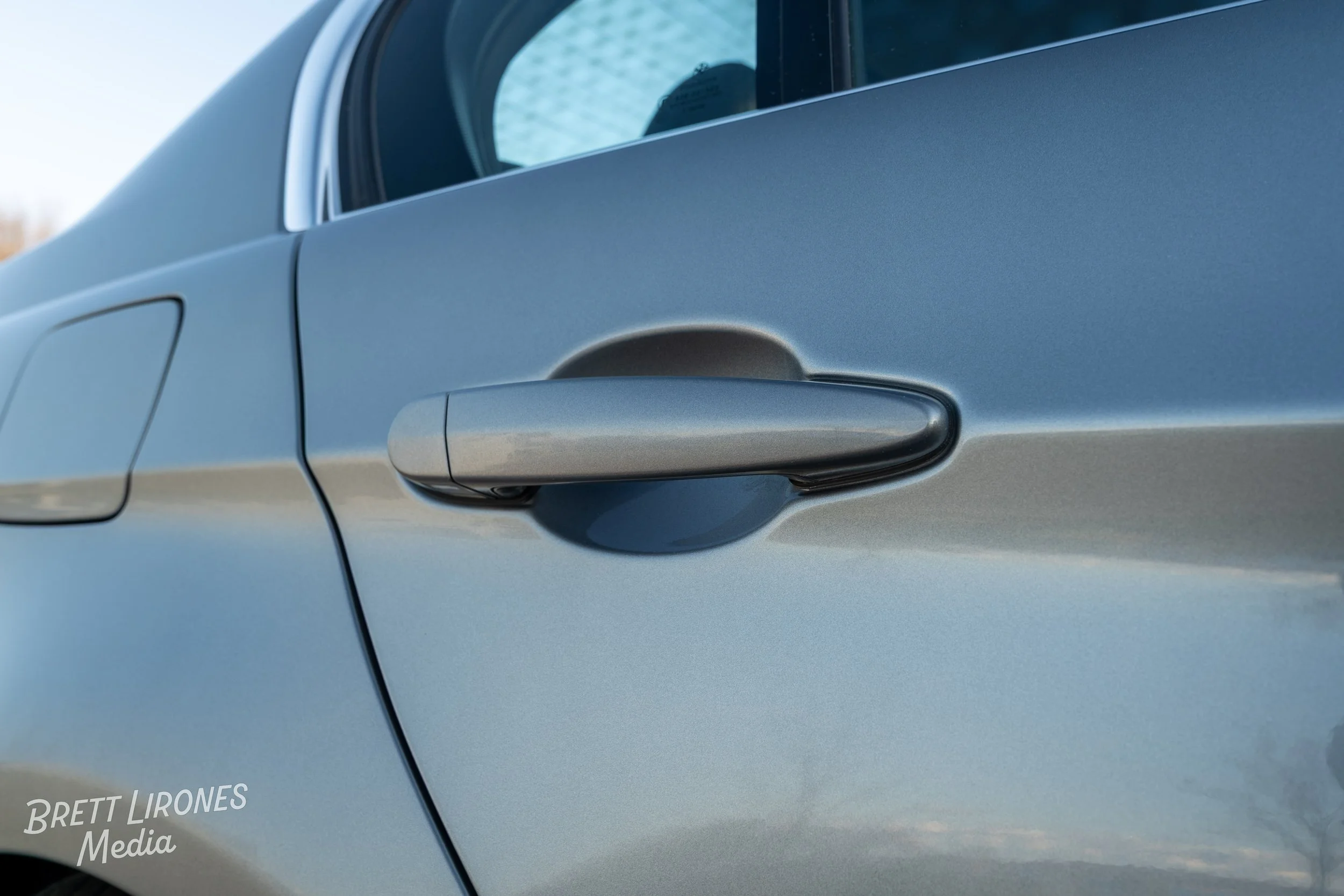Close-up of a silver car door handle on a metallic blue sedan.