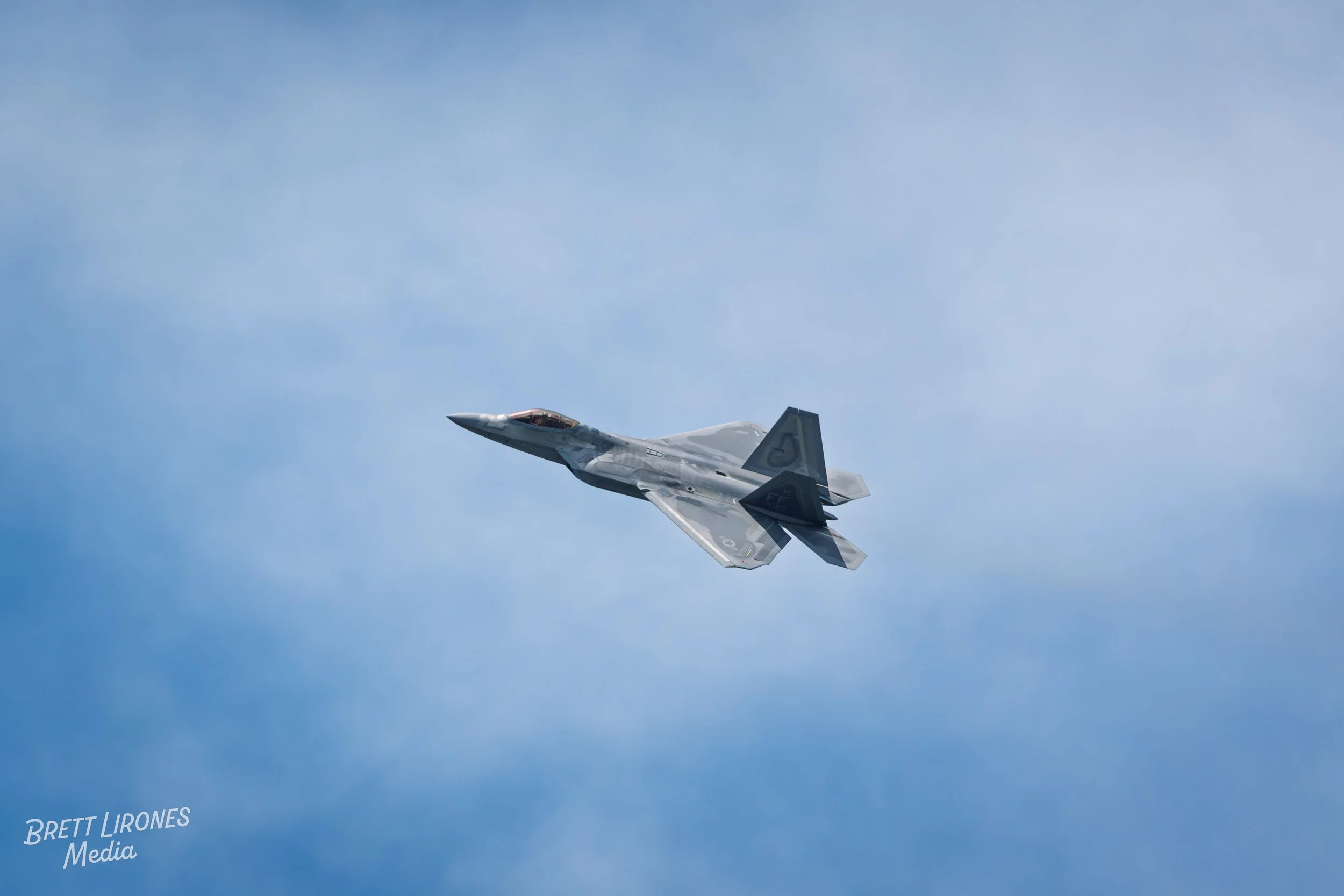 A military fighter jet flying through a cloudy sky.