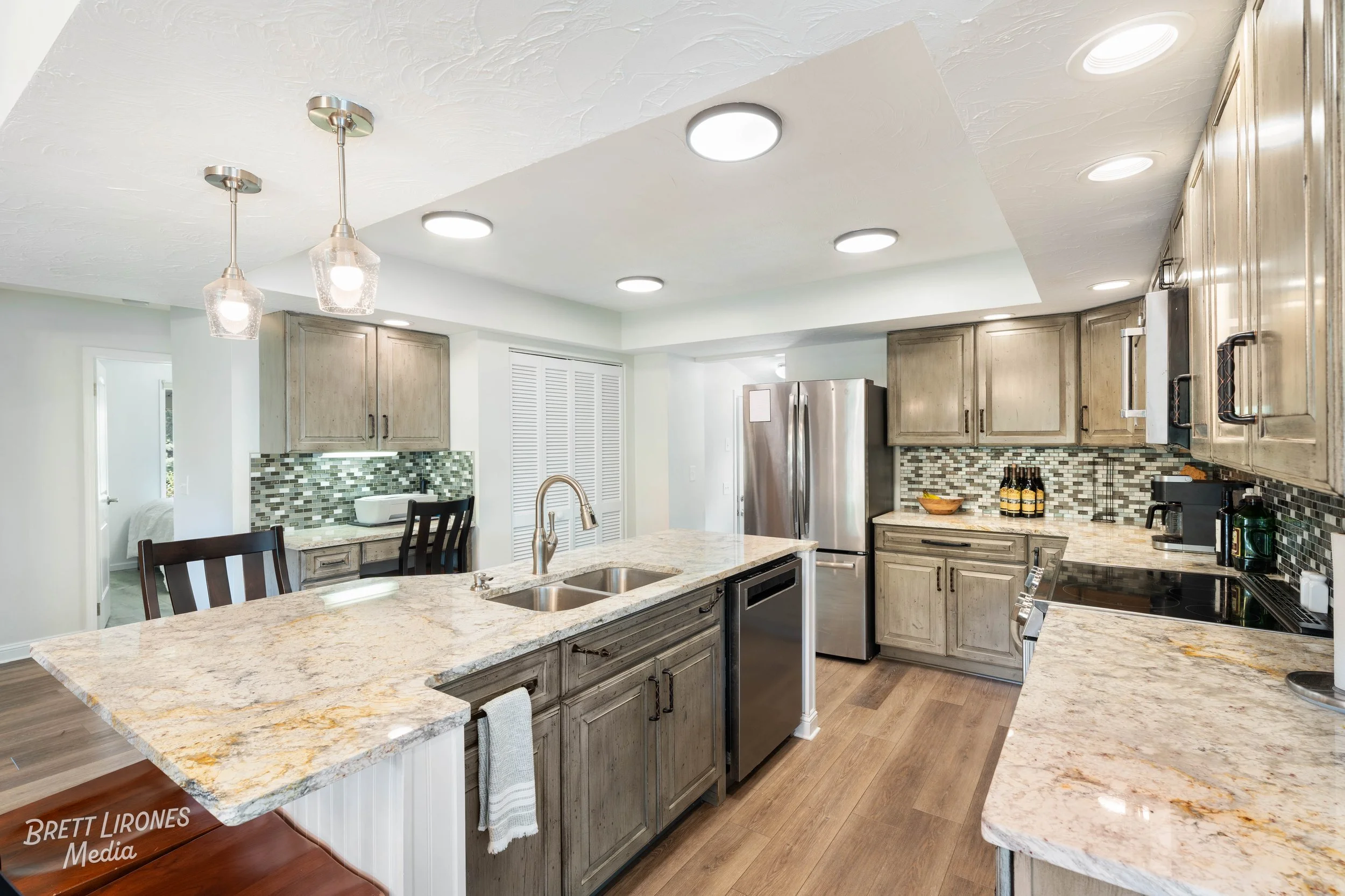 Modern kitchen with granite countertops, wooden cabinets, stainless steel appliances, tile backsplash, and pendant lights.