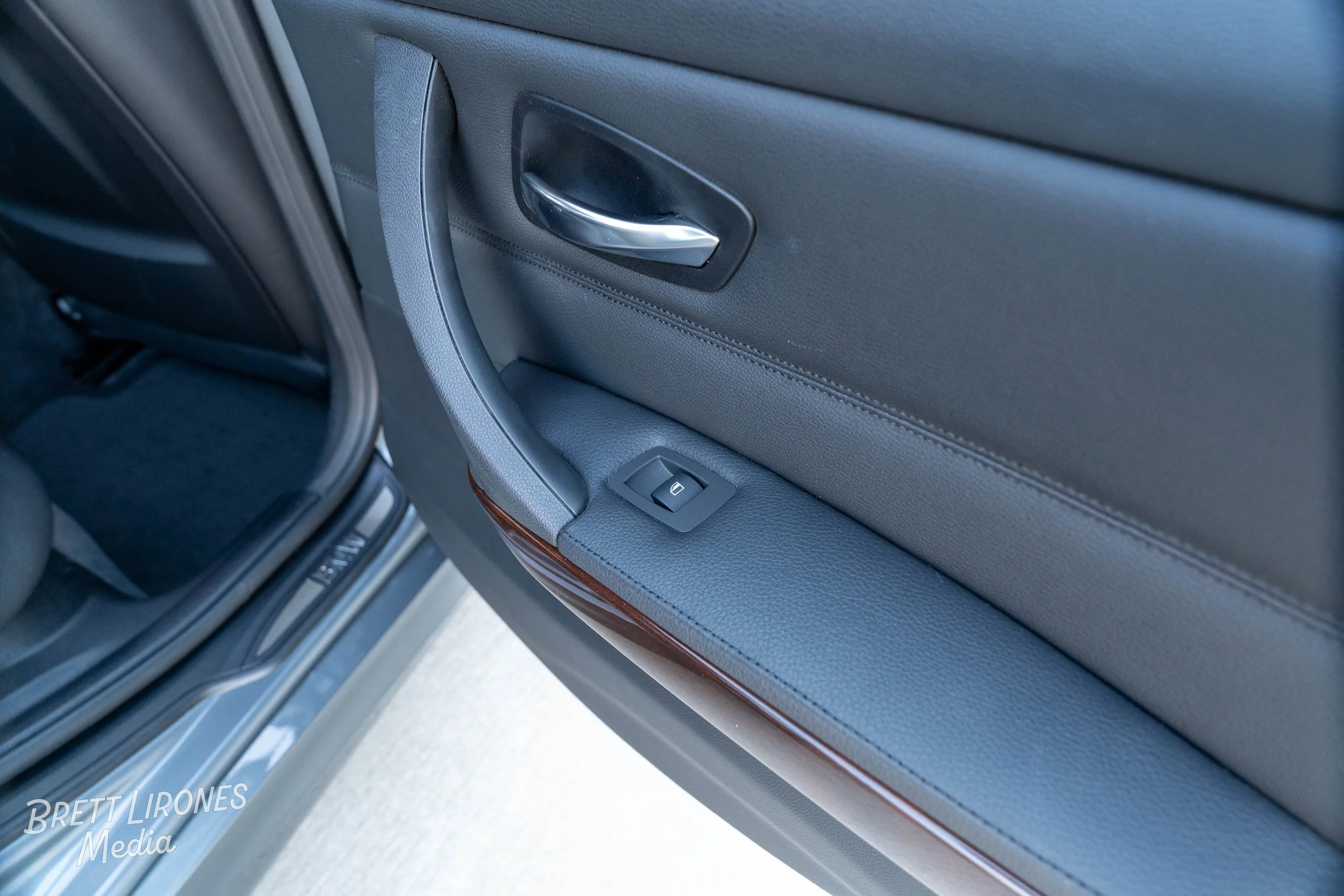 Close-up of a car's interior door panel showing a door handle, power window switch, and window trim.