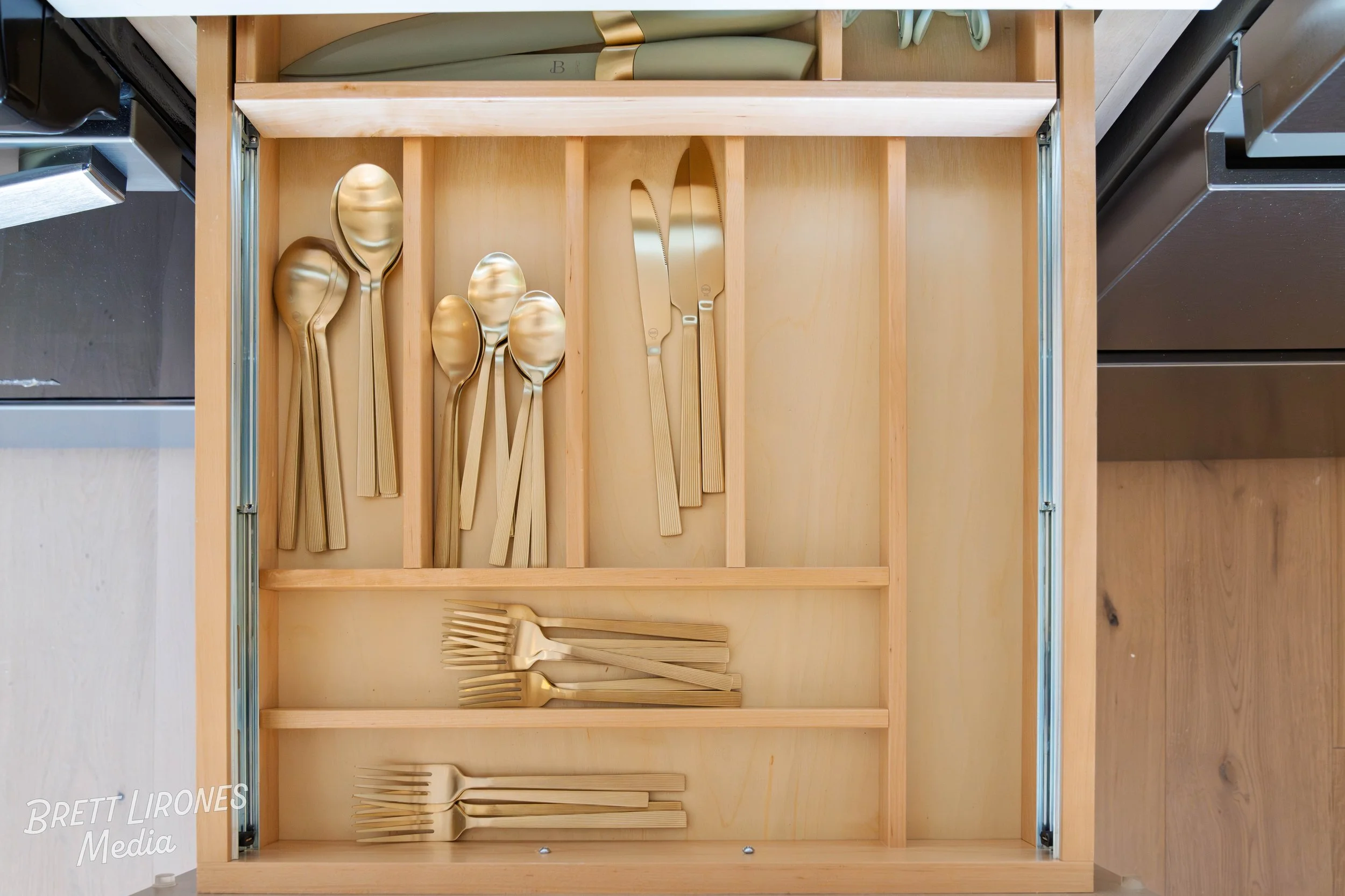 Drawer with spade, fork, and spoon utensils organized in compartments.
