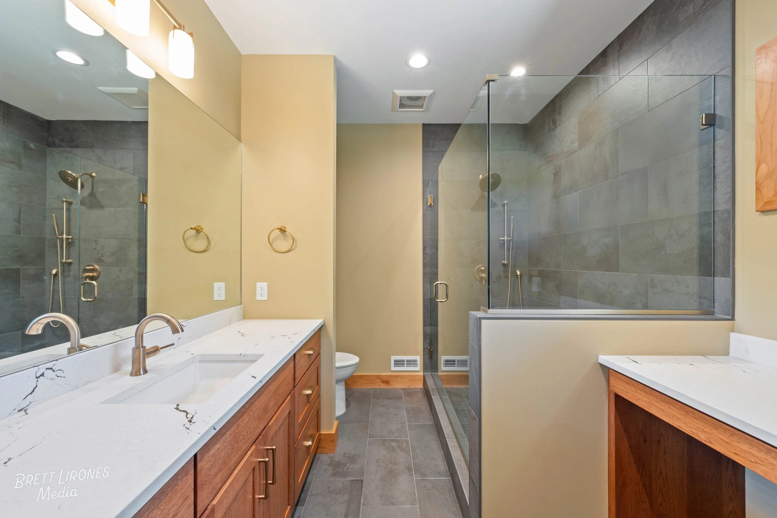 Modern bathroom with dual sinks, large mirror, and walk-in shower with glass enclosure