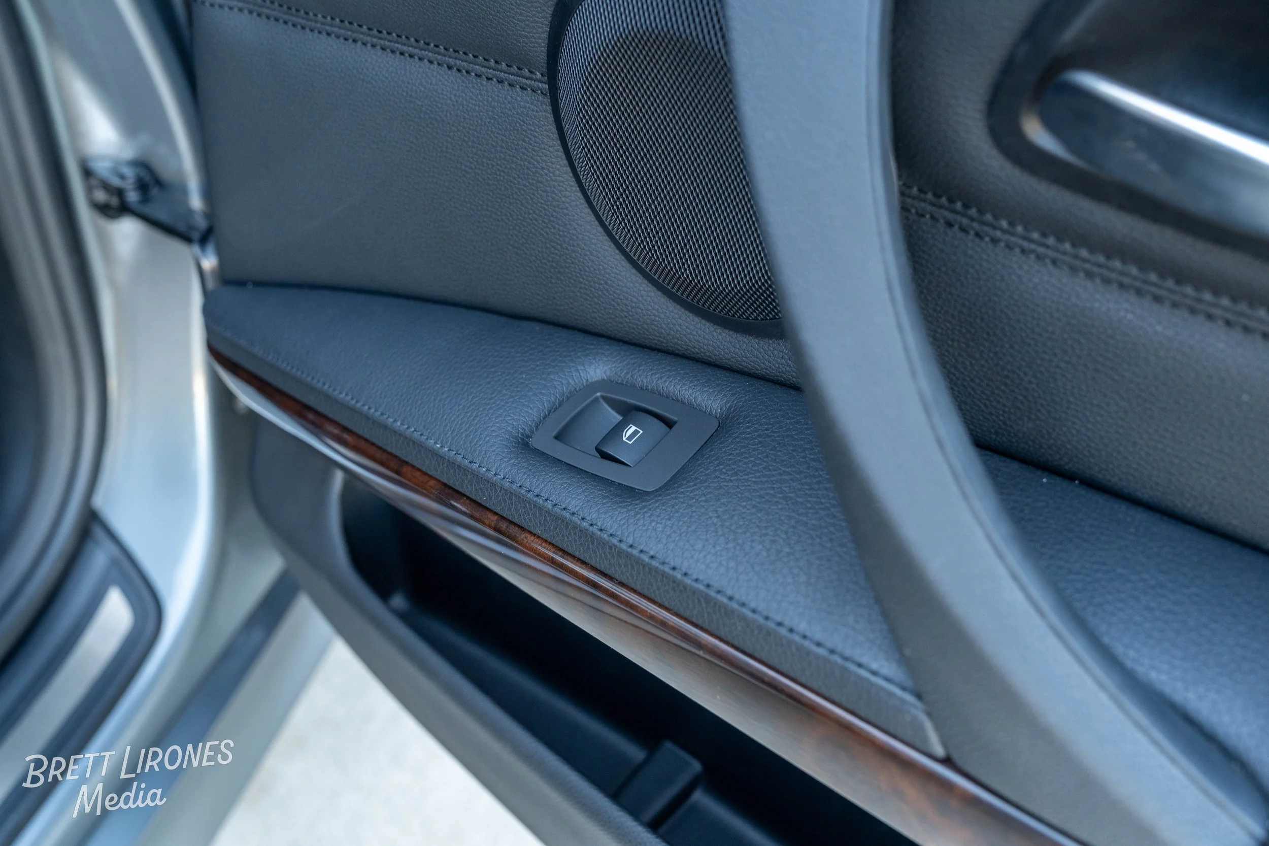 Close-up of a car door interior with a window control switch on the armrest.