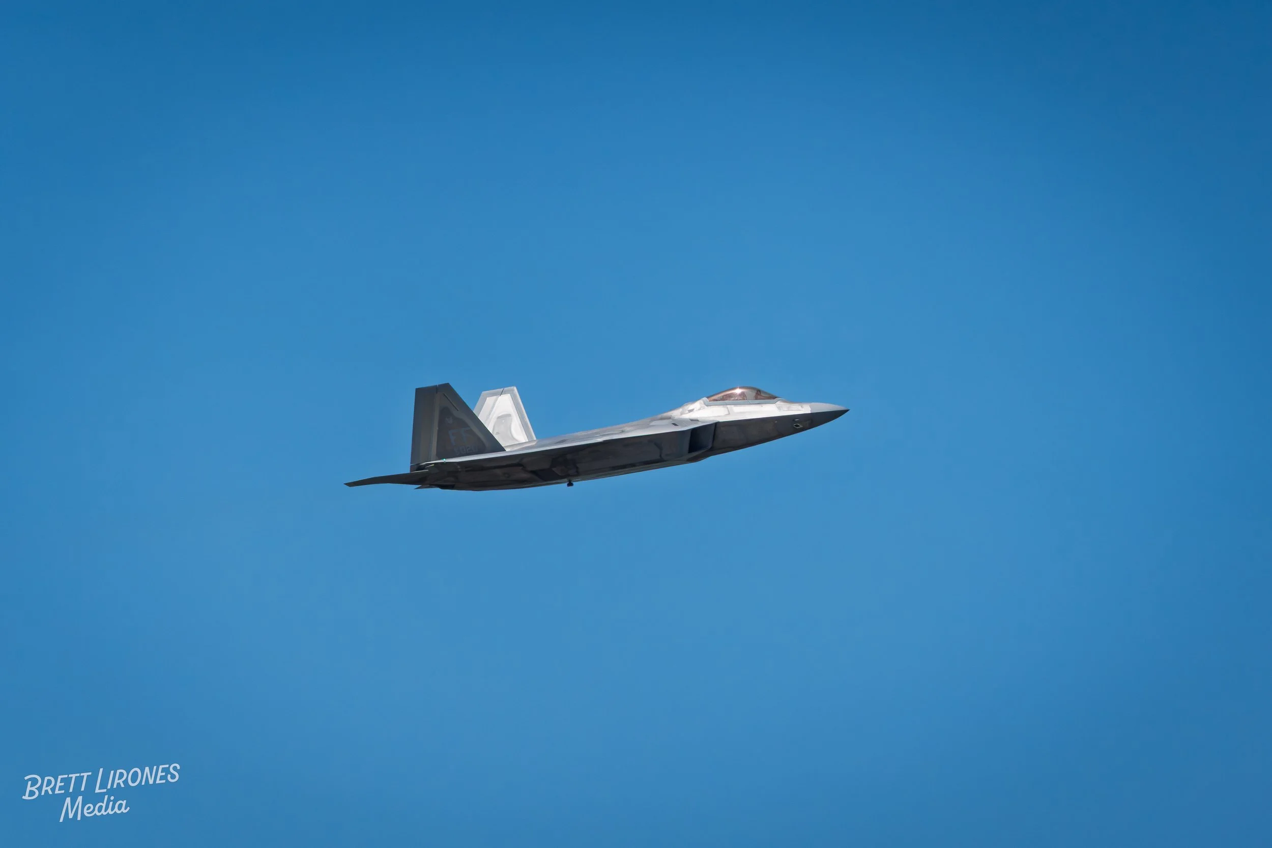 A fighter jet flying in a clear blue sky.