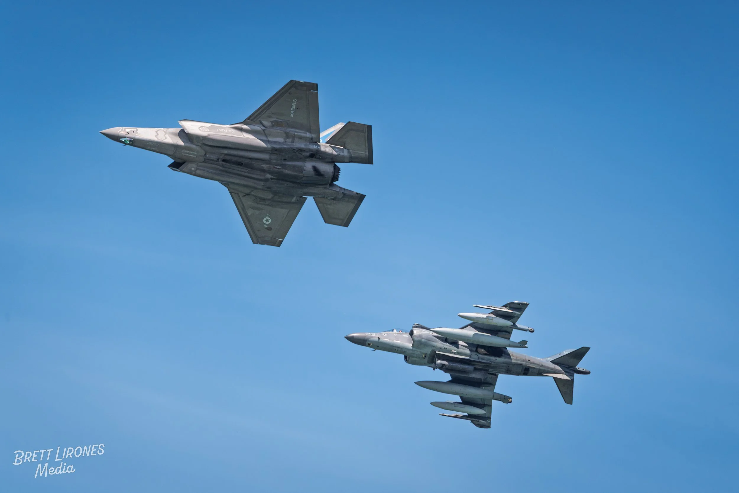 Two fighter jets flying in formation in a clear blue sky.
