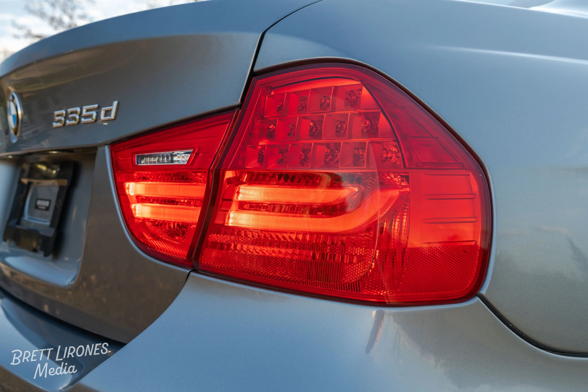 Close-up of the rear right side of a silver BMW 3 Series vehicle, focusing on the tail light and badge