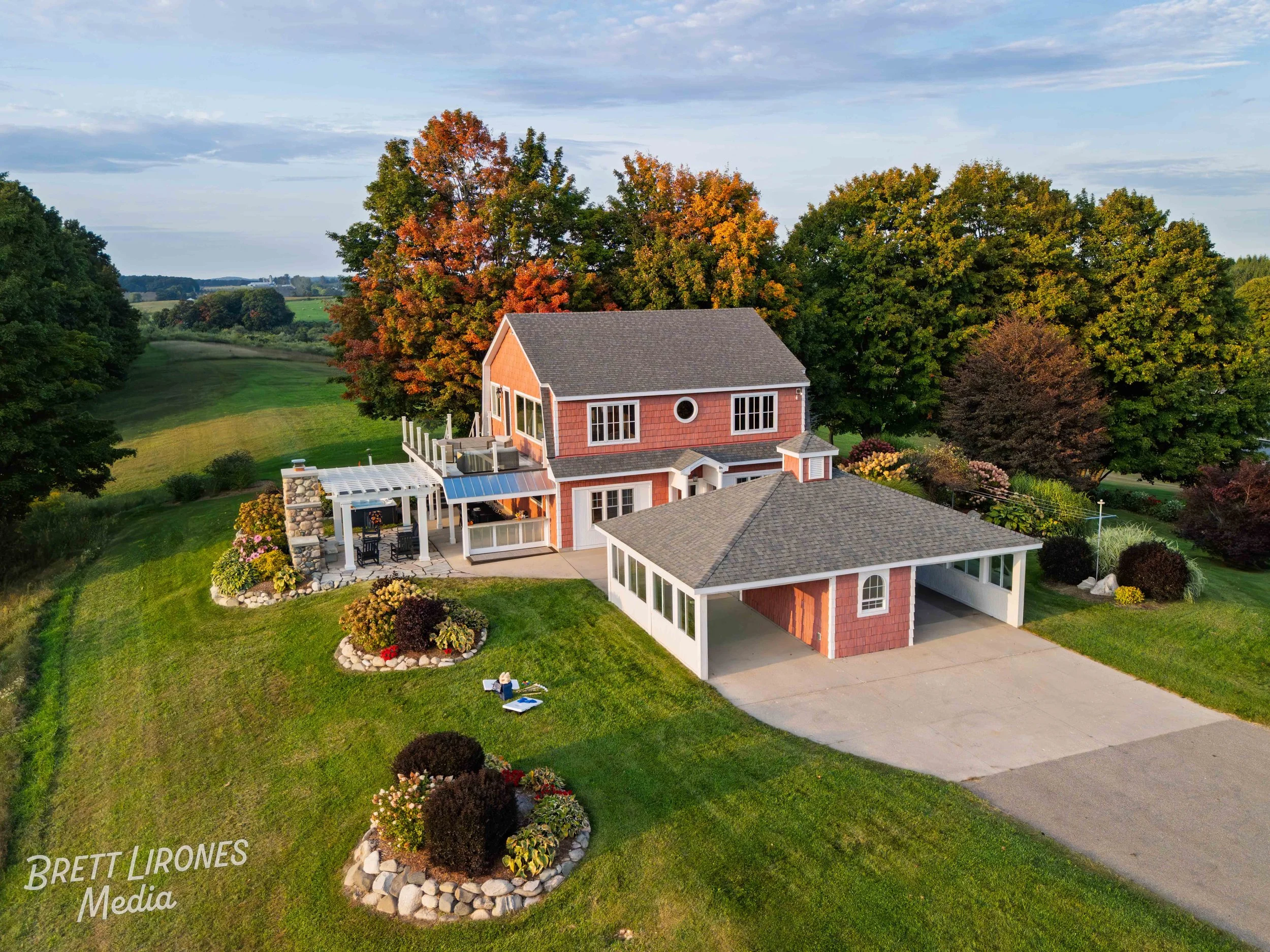 A two-story house with a garage and a backyard patio surrounded by trees and landscaped garden, during autumn.
